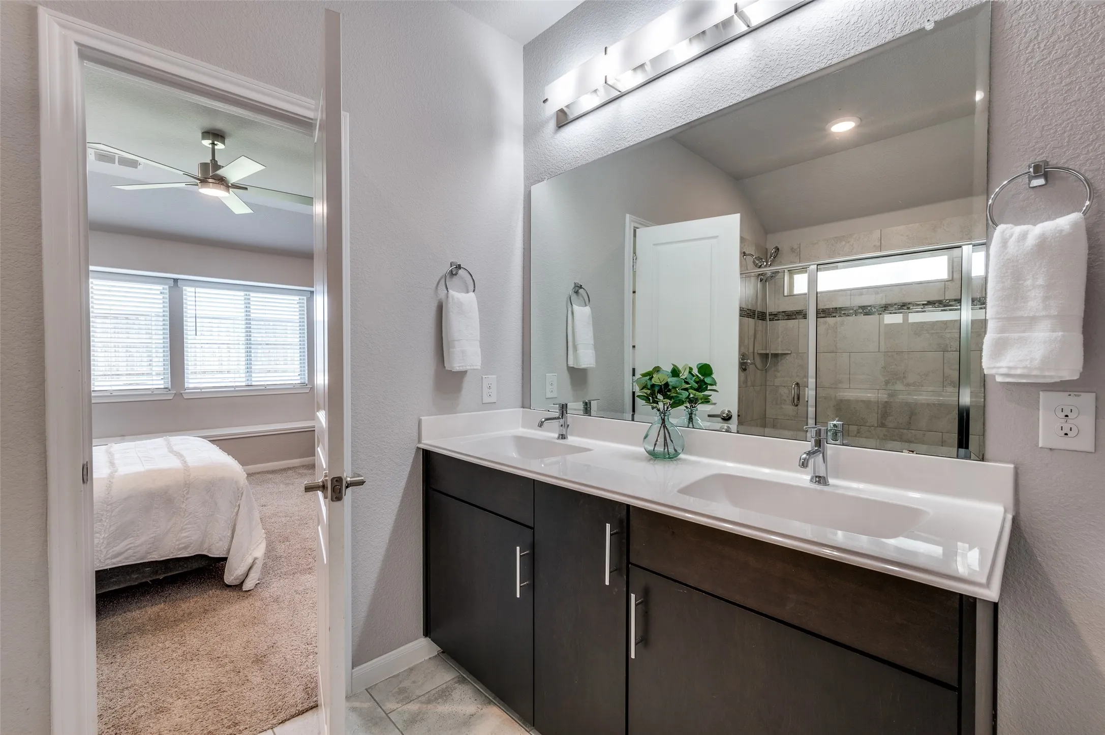 Dual vanity with integrated sinks, white countertops, dark wood-finish cabinetry, and chrome fixtures