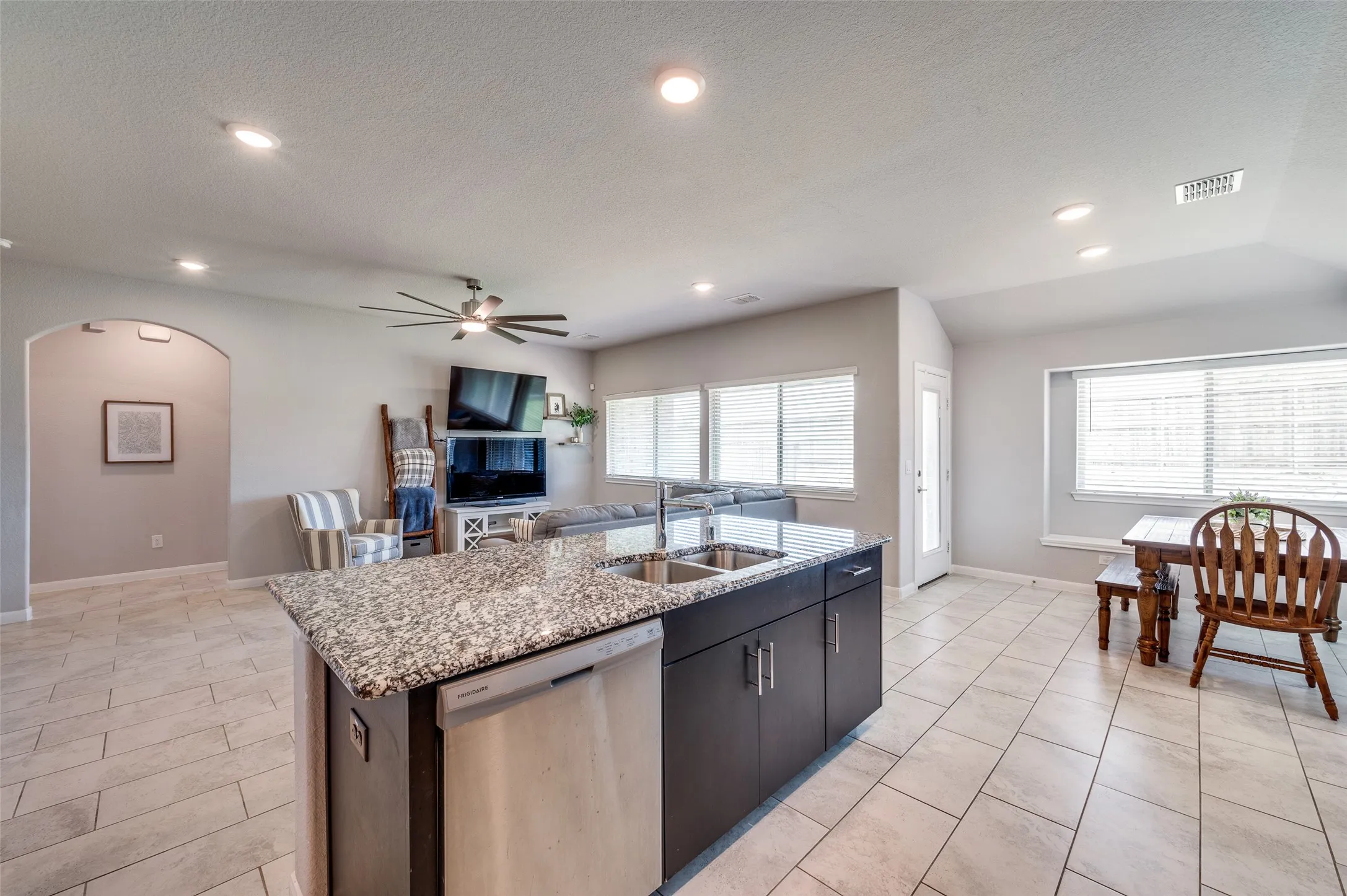 Central kitchen island with a granite-style countertop and dual stainless steel sinks