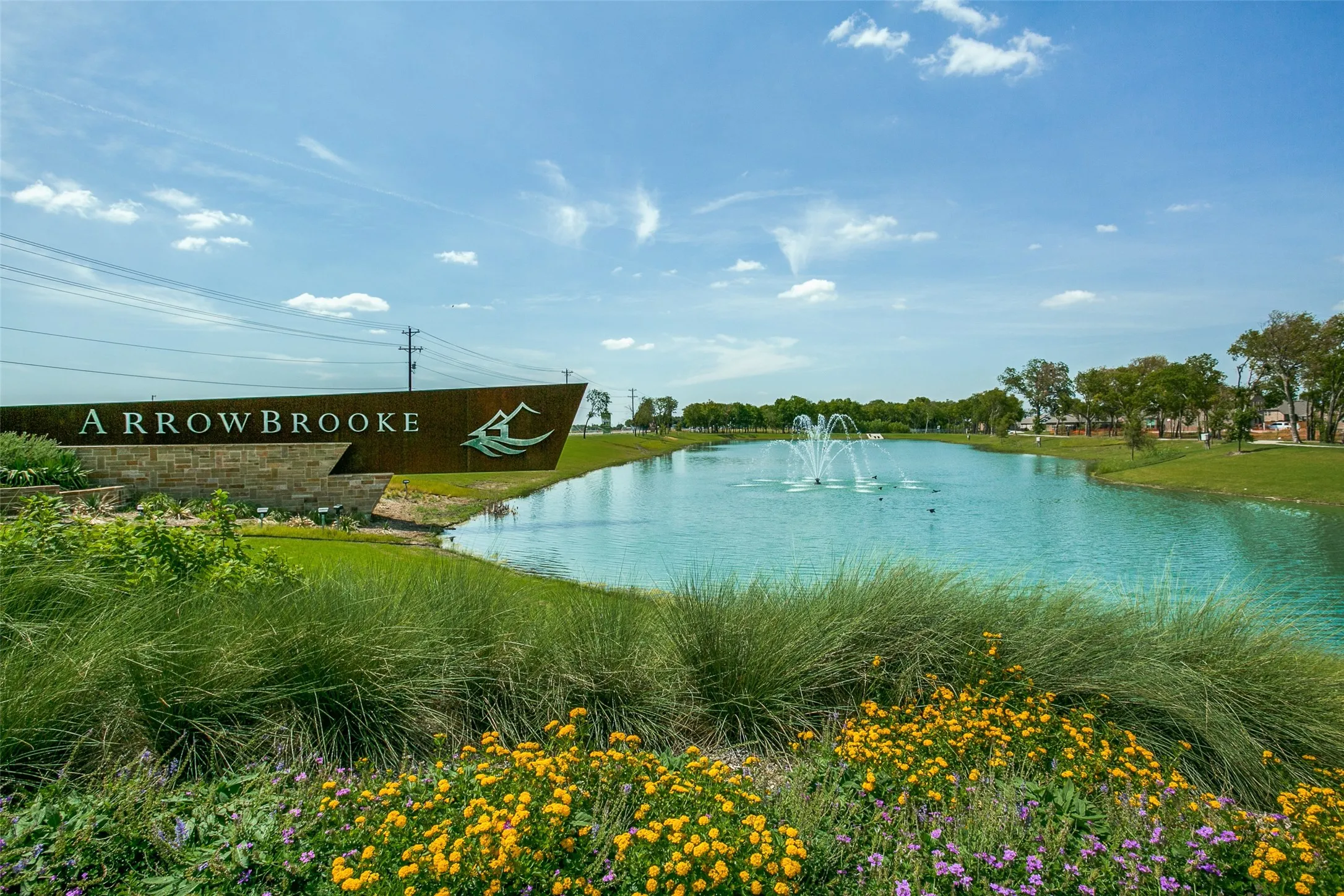 Lakeside community entrance featuring a decorative fountain and mature landscaping
