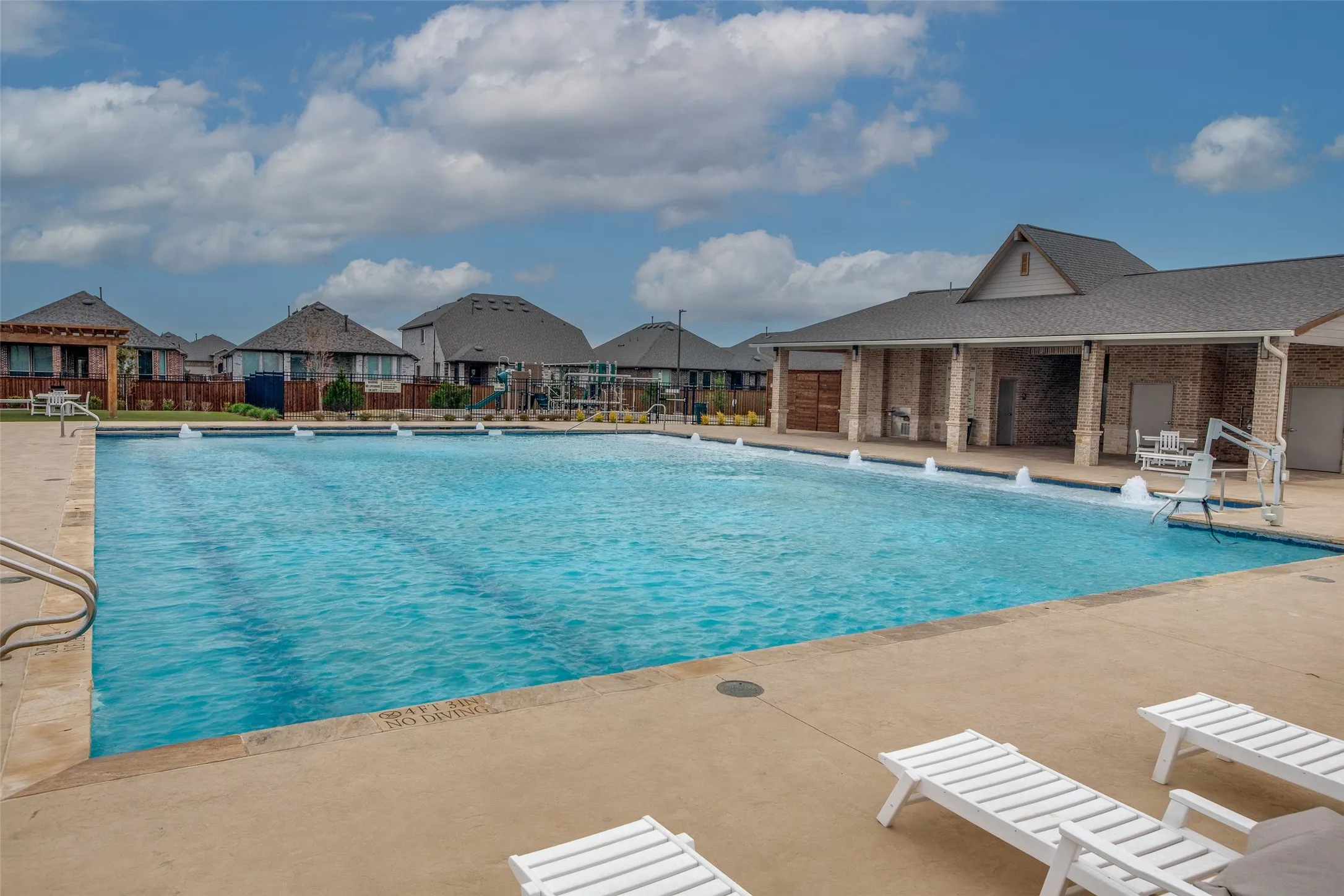 Expansive outdoor swimming pool with a surrounding concrete deck and integrated water features