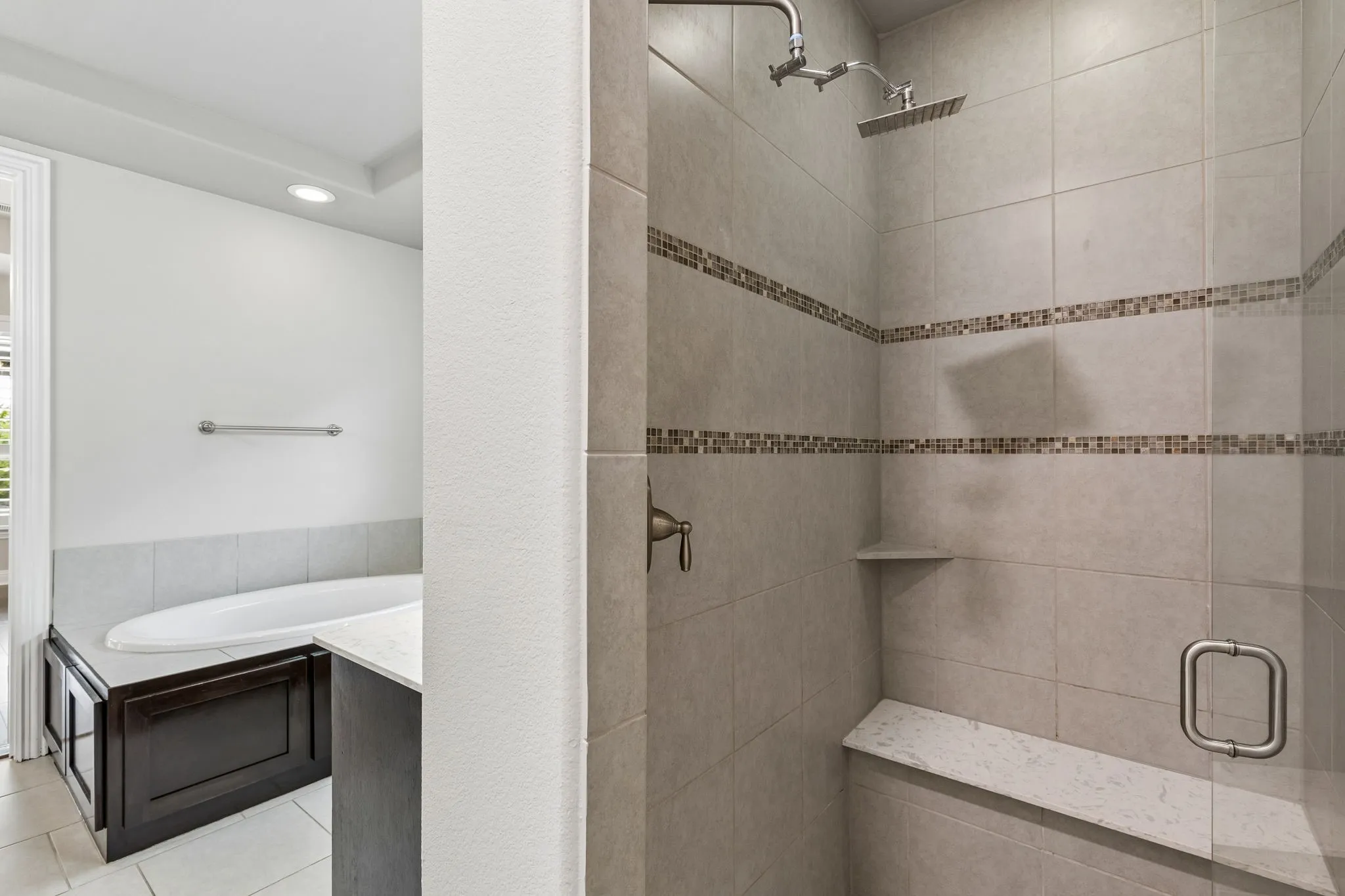 The primary bath features a spacious walk-in tiled shower with bench seating and frameless​​‌​​​​‌​​‌‌​‌‌​​​‌‌​‌​‌​‌​​​‌​​ glass.