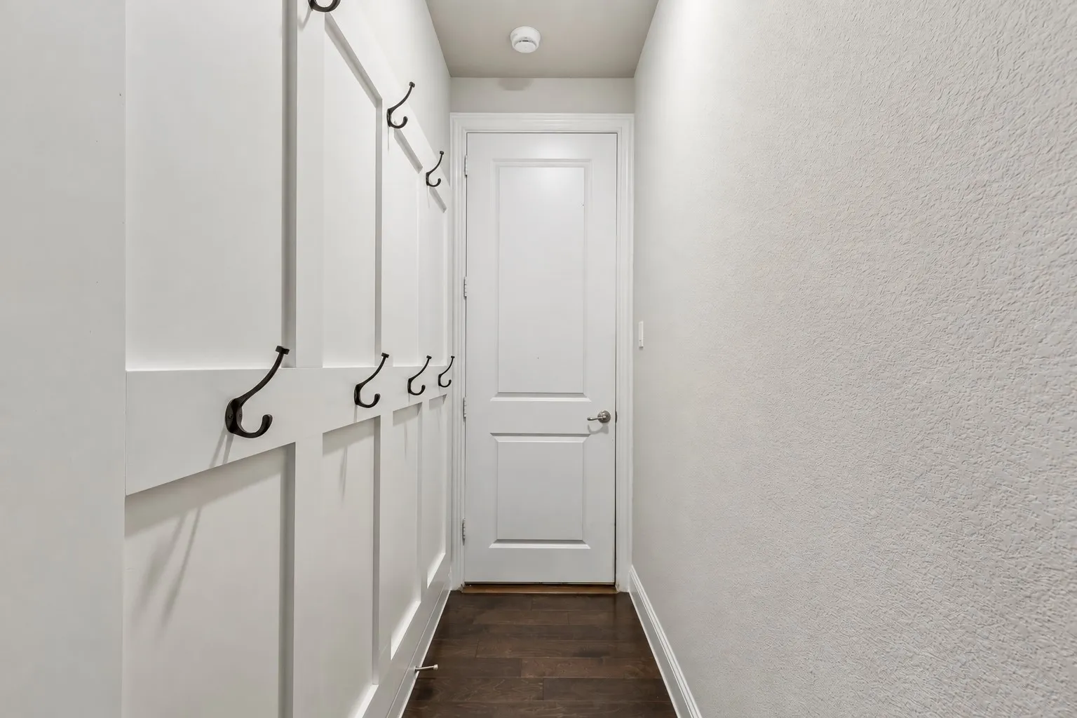 A dedicated mudroom/drop zone offers built-in board-and-batten detail with multiple hooks, creating a convenient everyday landing space just off the garage