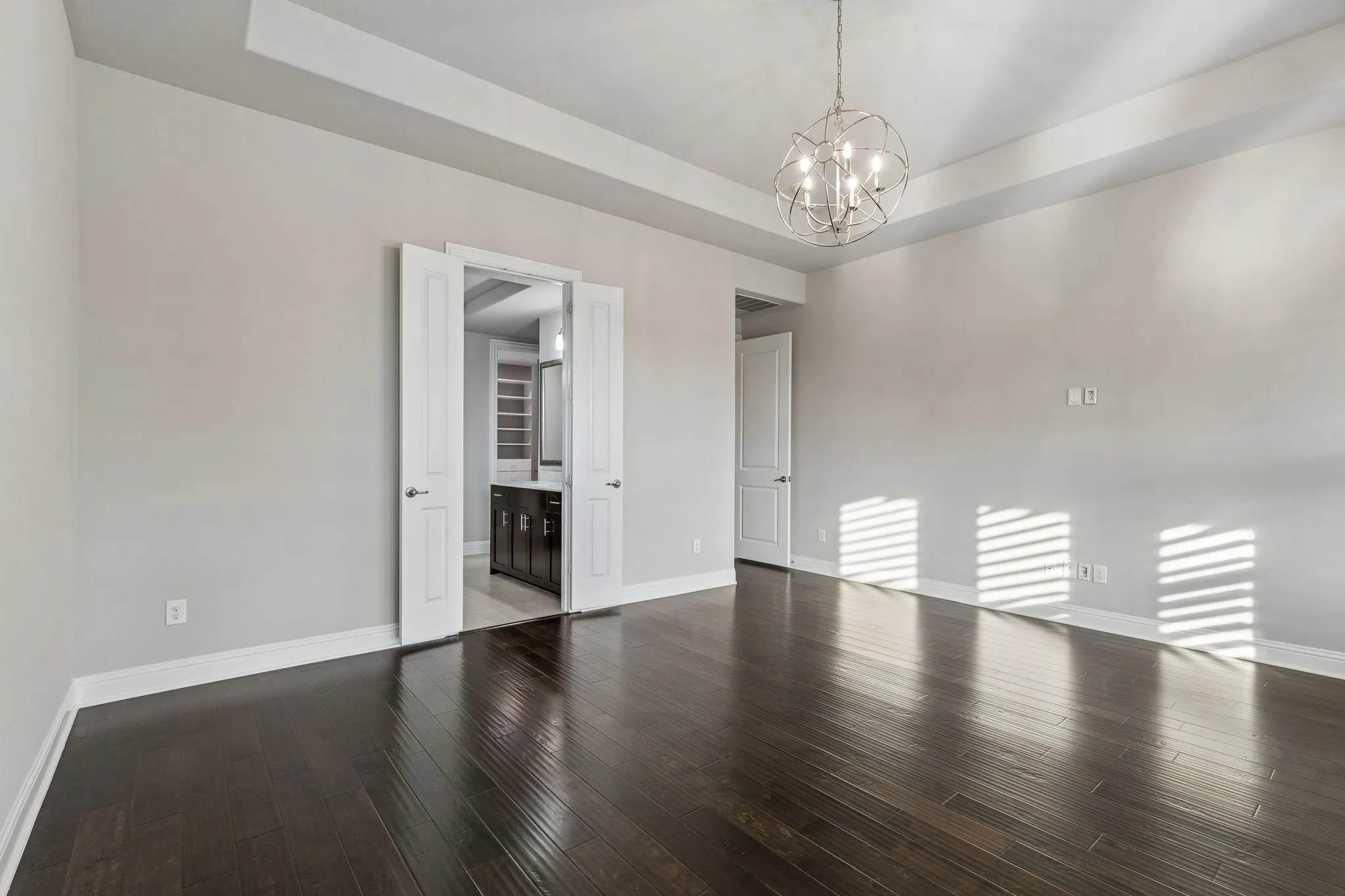 The spacious first-floor primary suite features hardwood floors, a tray ceiling and direct access to the en suite bath and custom closet.
