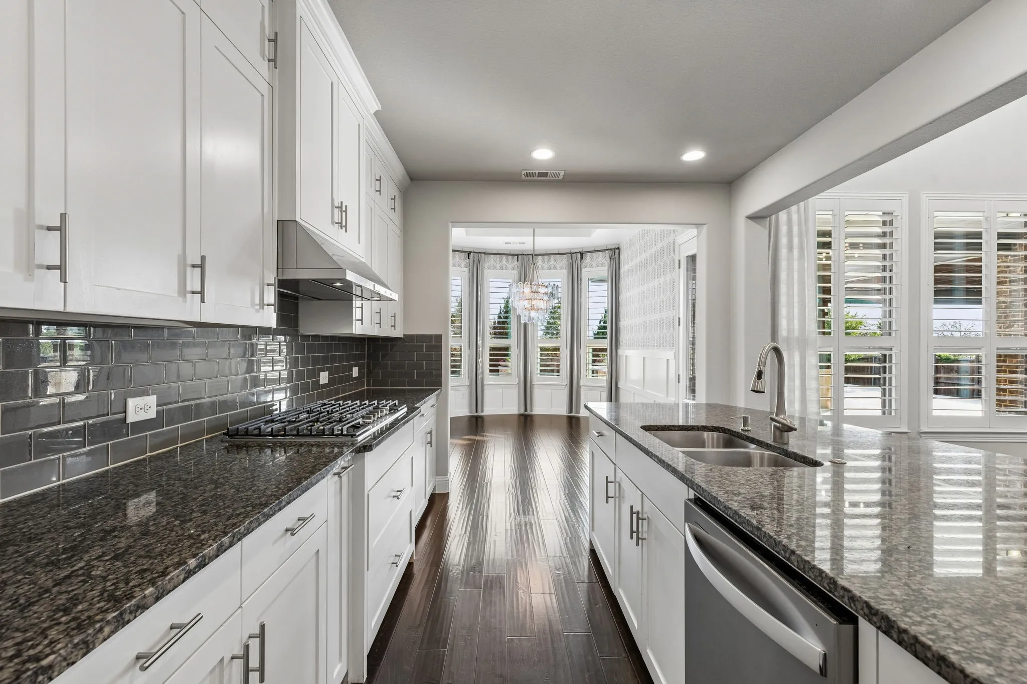The kitchen’s granite surfaces, ceiling-height cabinetry and 2026 gas cooktop flow seamlessly into the designer-finished dining room beyond