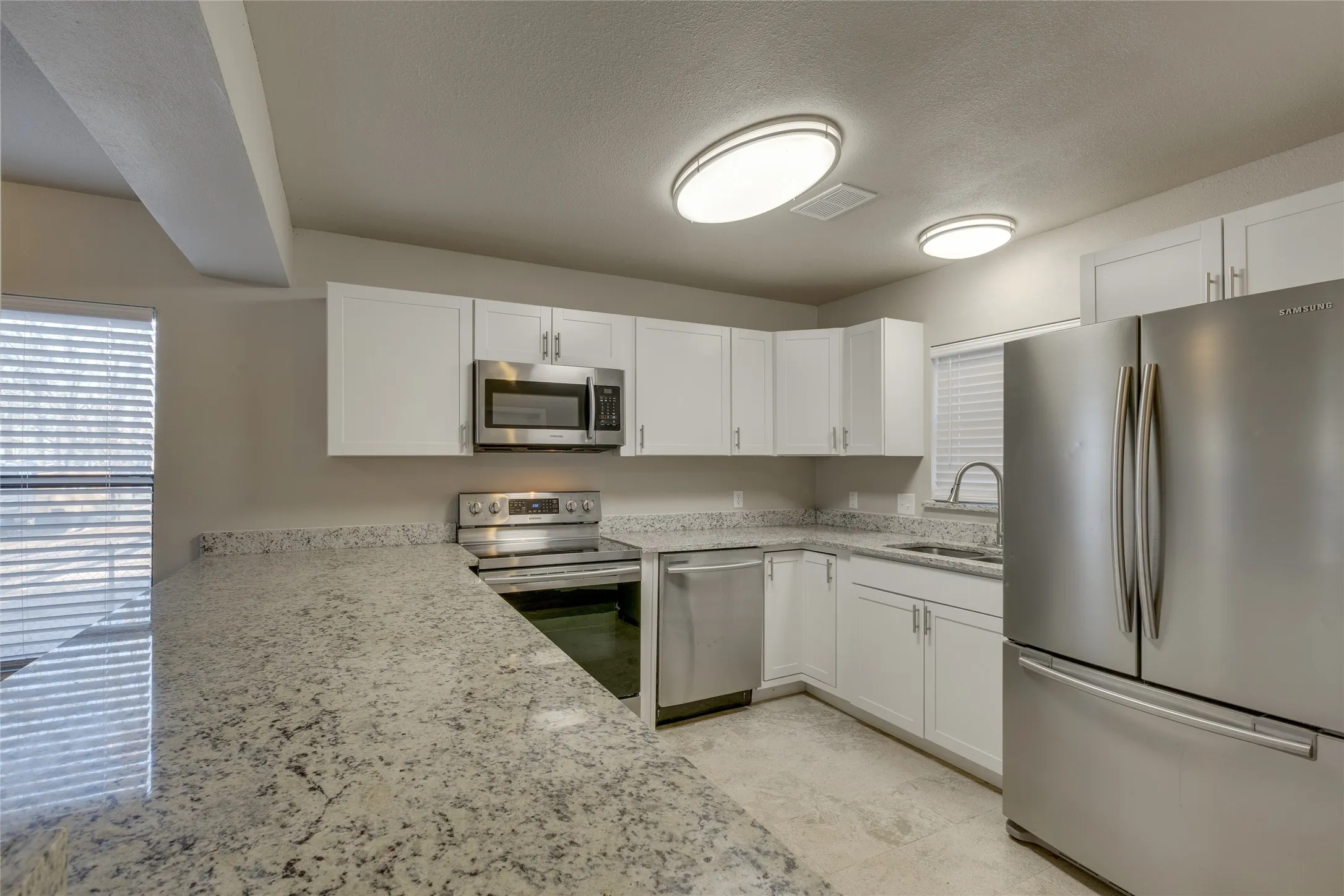 Kitchen with appliances with stainless steel finishes, white cabinets, and granite counters