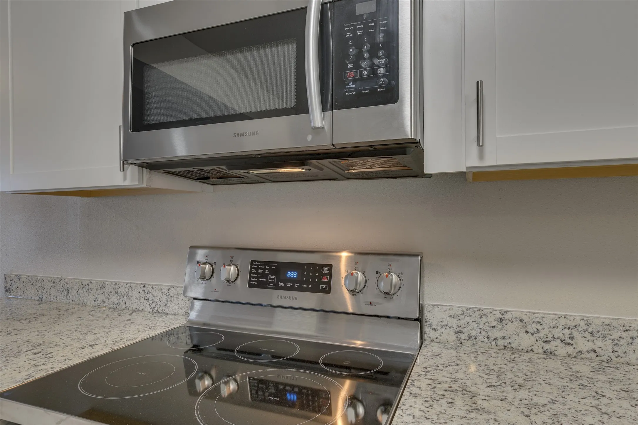 Kitchen view of appliances with stainless steel finishes, light stone countertops, and white cabinetry