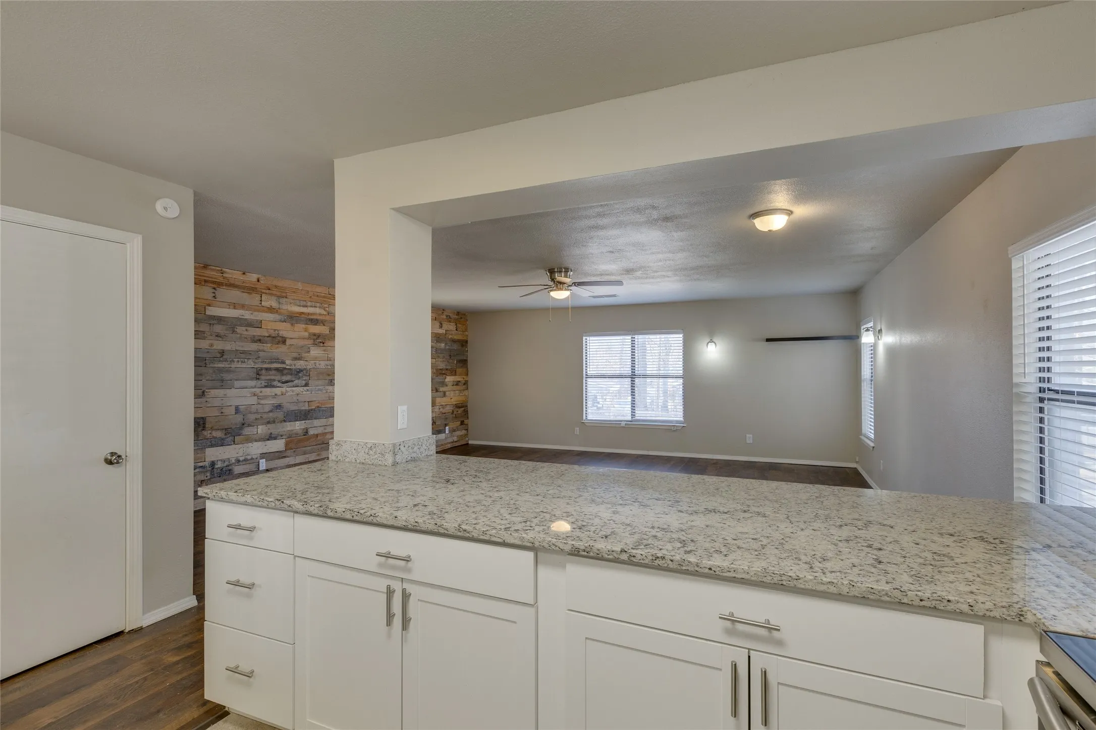 Kitchen featuring dark wood-type flooring, white cabinetry, light stone countertops, and open floor plan