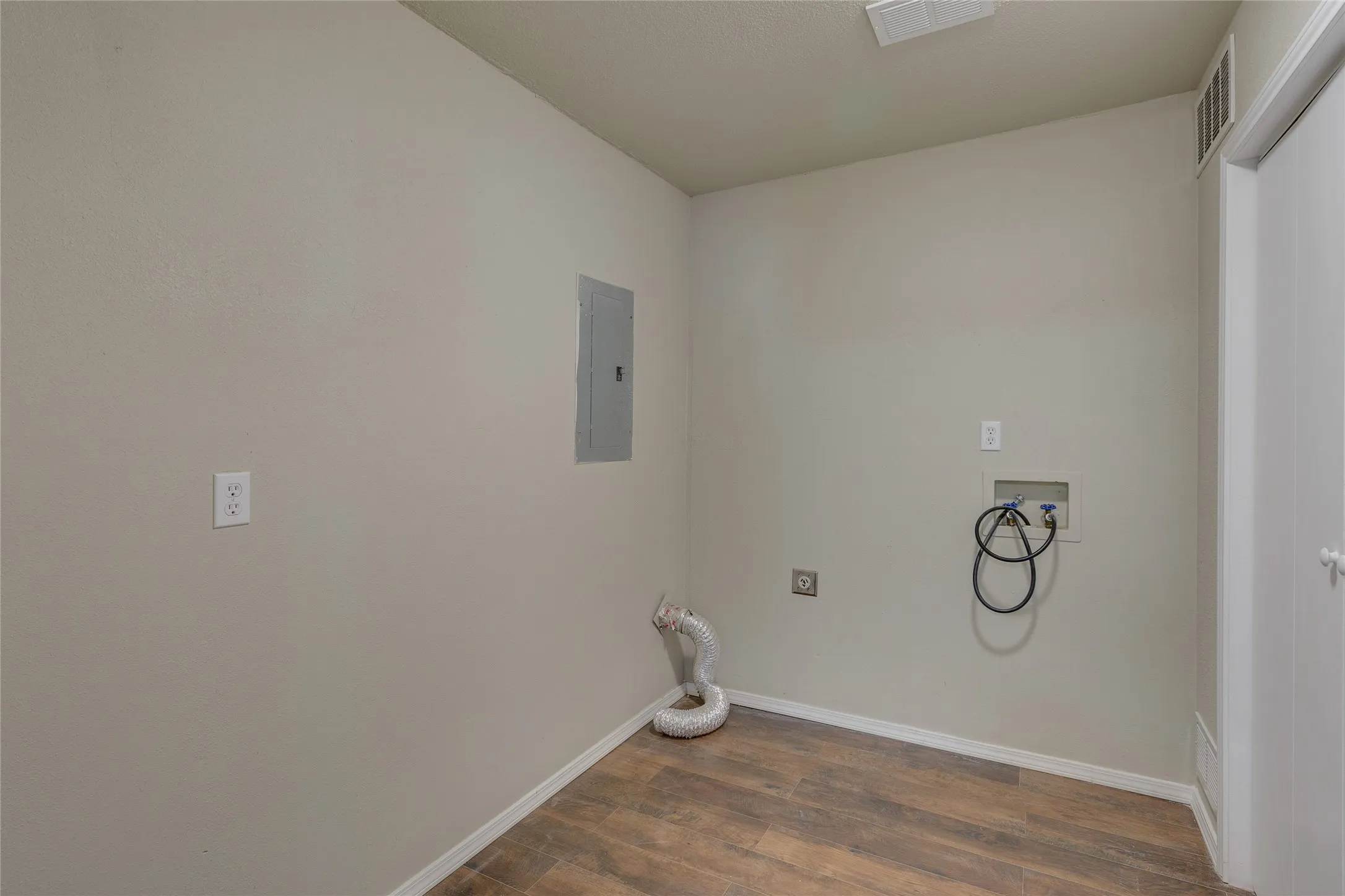 Washroom featuring dark wood-type flooring, washer hookup, and electric panel