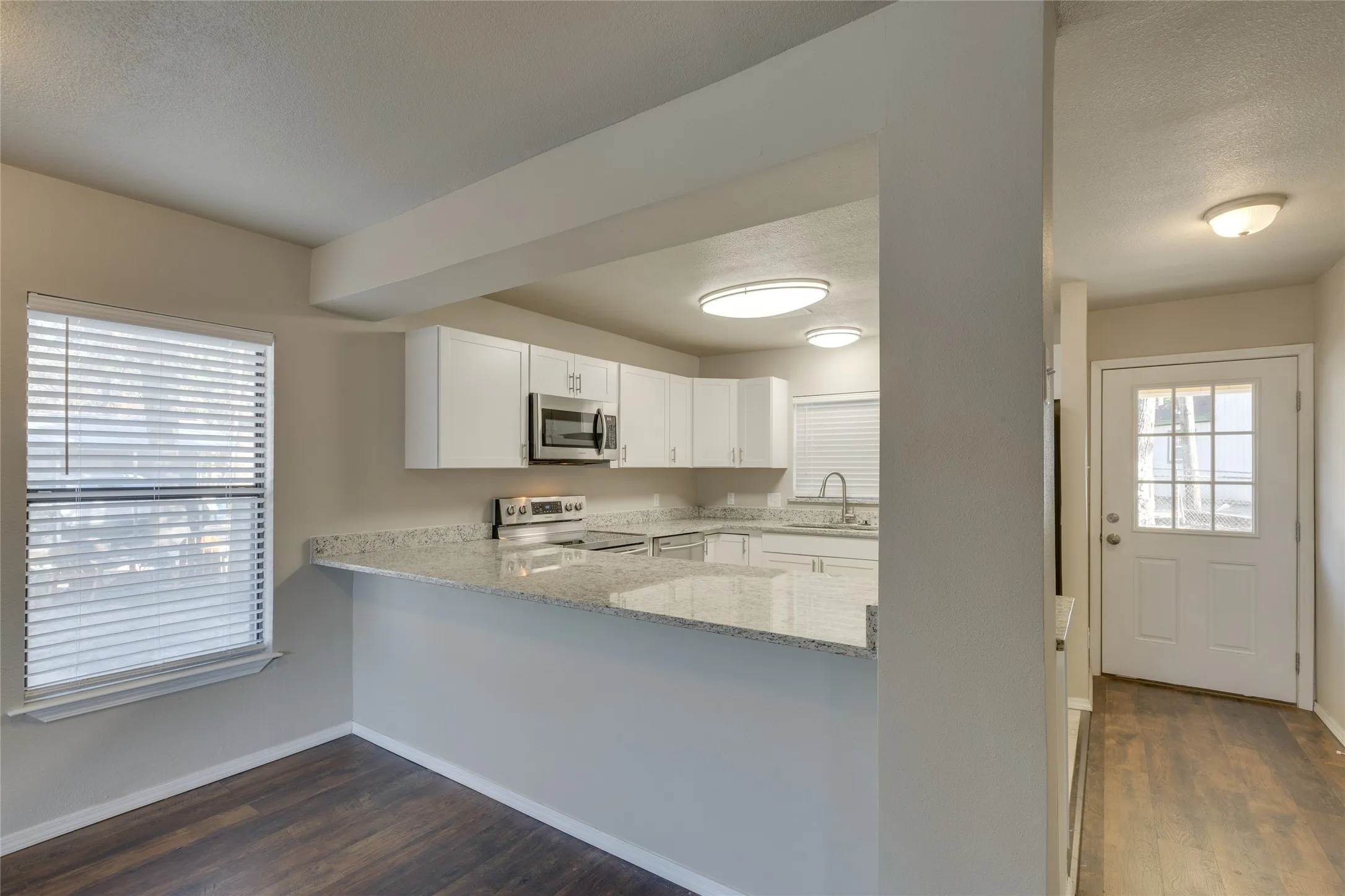 Kitchen with granite countertops, white cabinets, dark wood-type flooring and breakfast bar