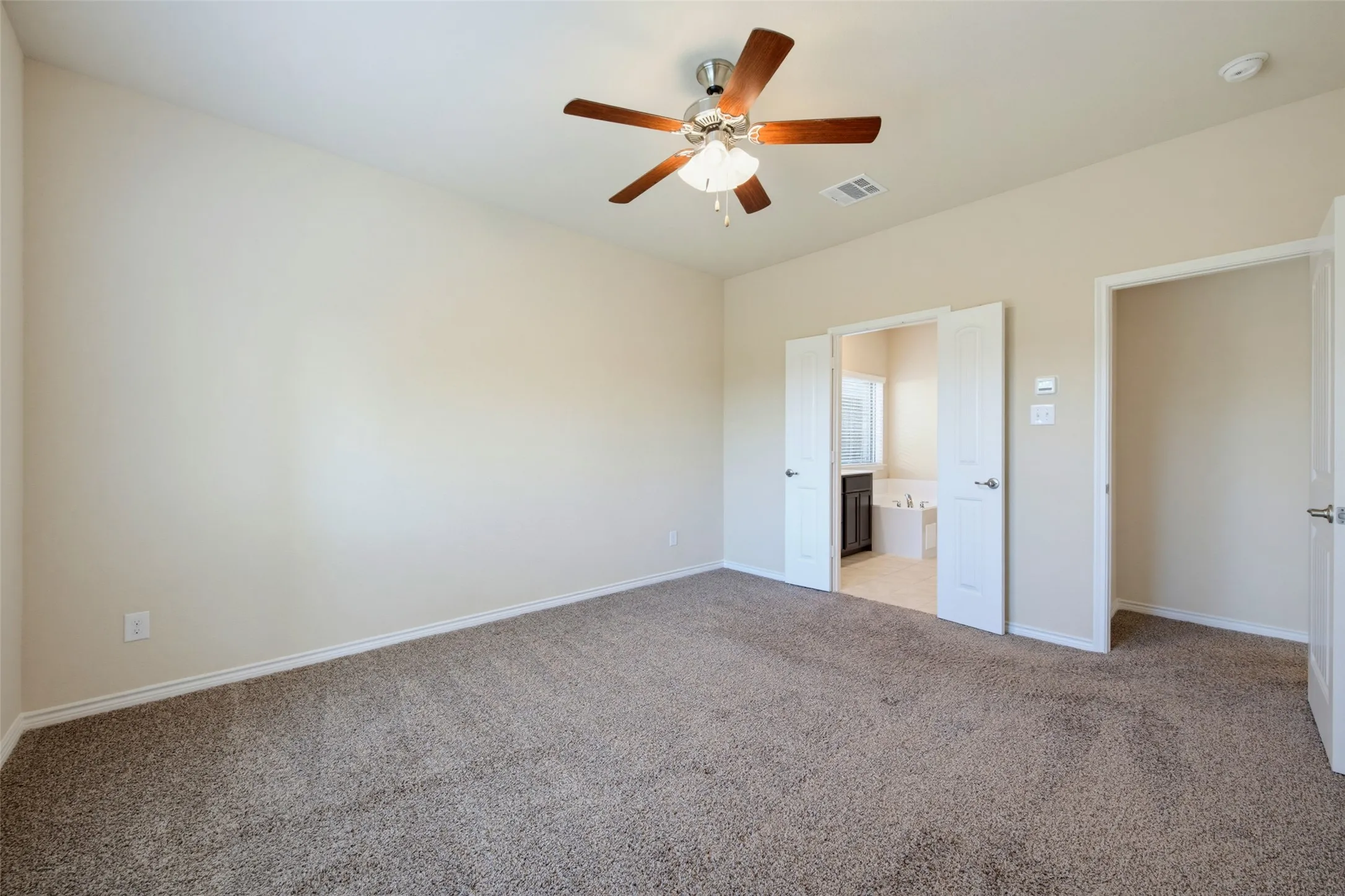 Neutral wall tones, carpeted flooring, ceiling fan with light fixture, double doors, and additional doorway