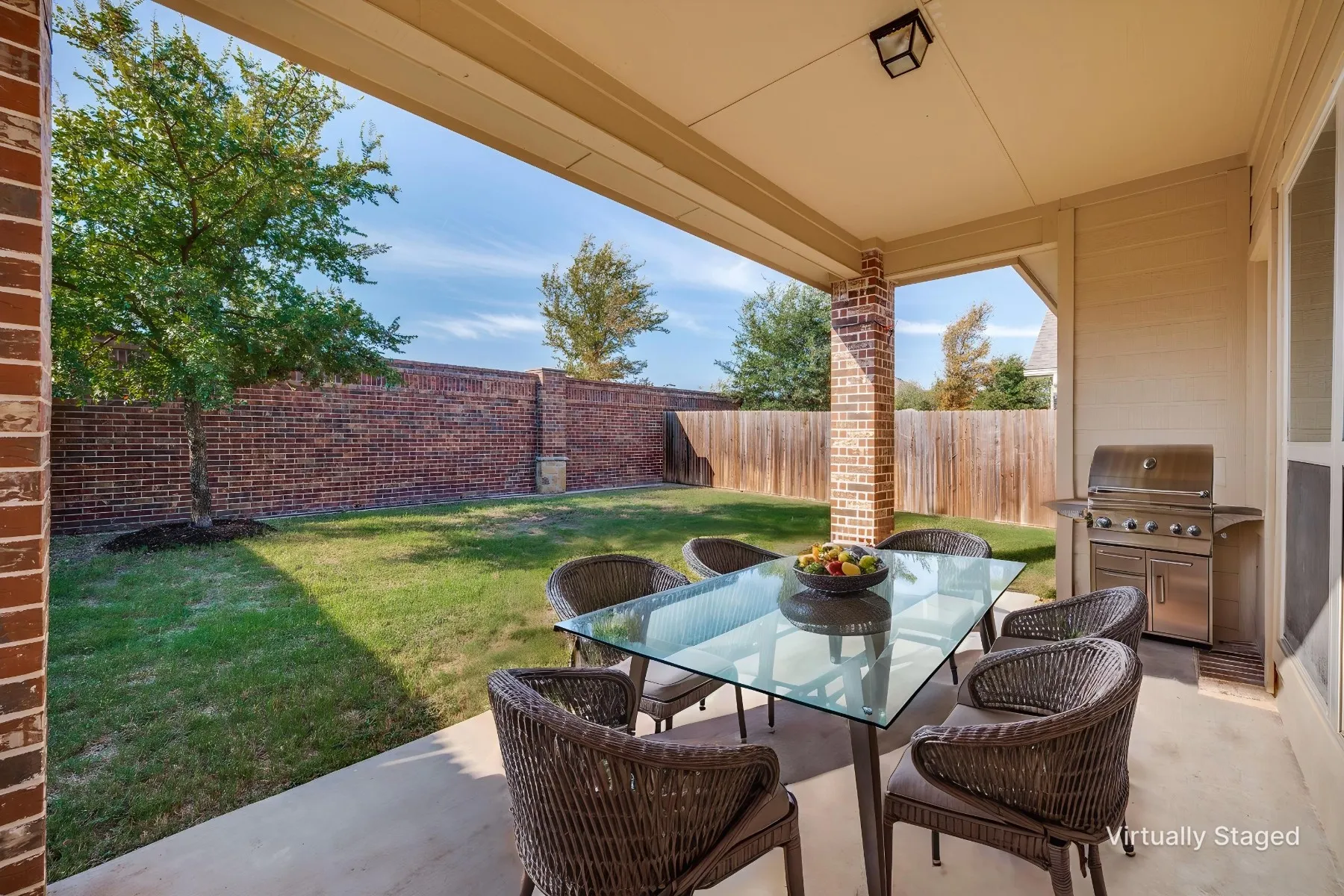 Covered patio with a concrete surface, brick support column, and overhead lighting