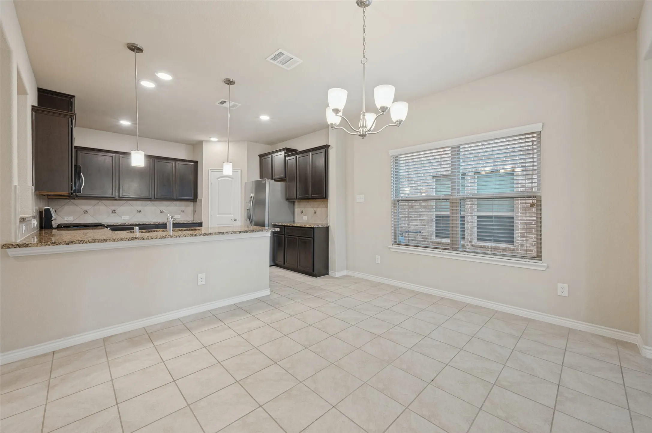 Kitchen with dark wood cabinetry, stainless steel appliances, and stone countertops
