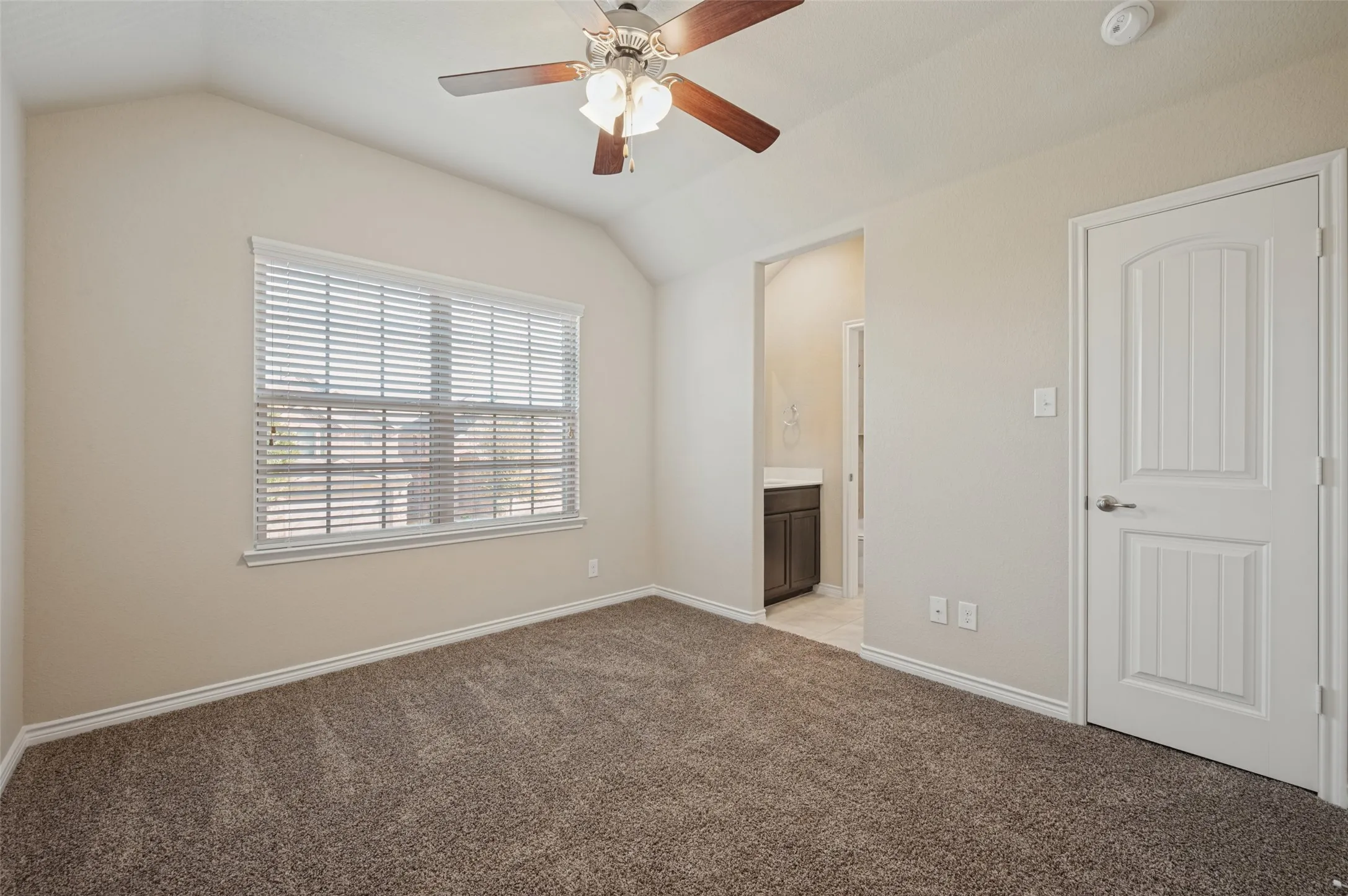 Vaulted ceiling with a ceiling fan, carpet flooring, window with blinds, and white panel doors
