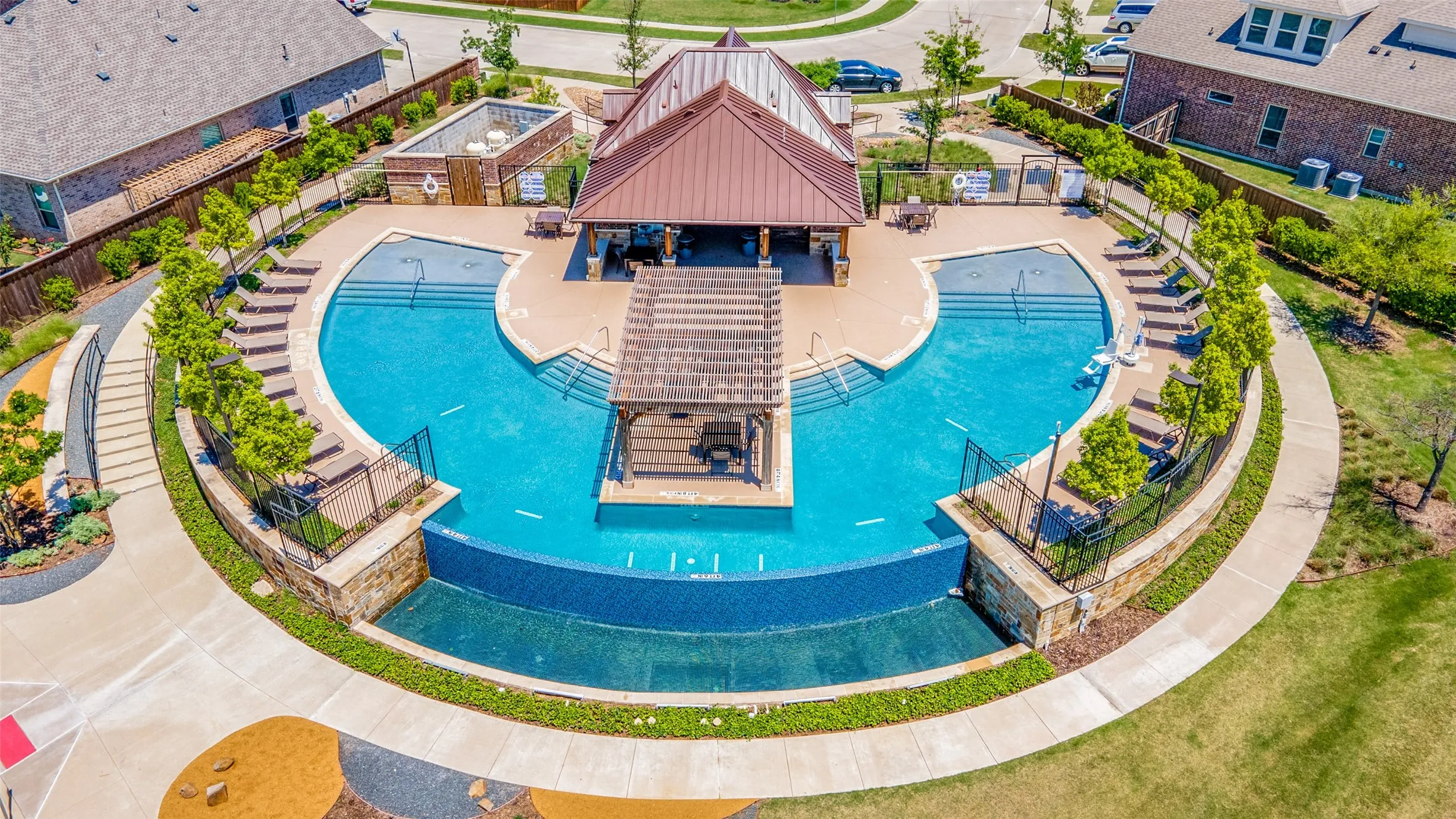Multi-level pool area featuring a shaded pavilion, sun deck, and a cascading water feature