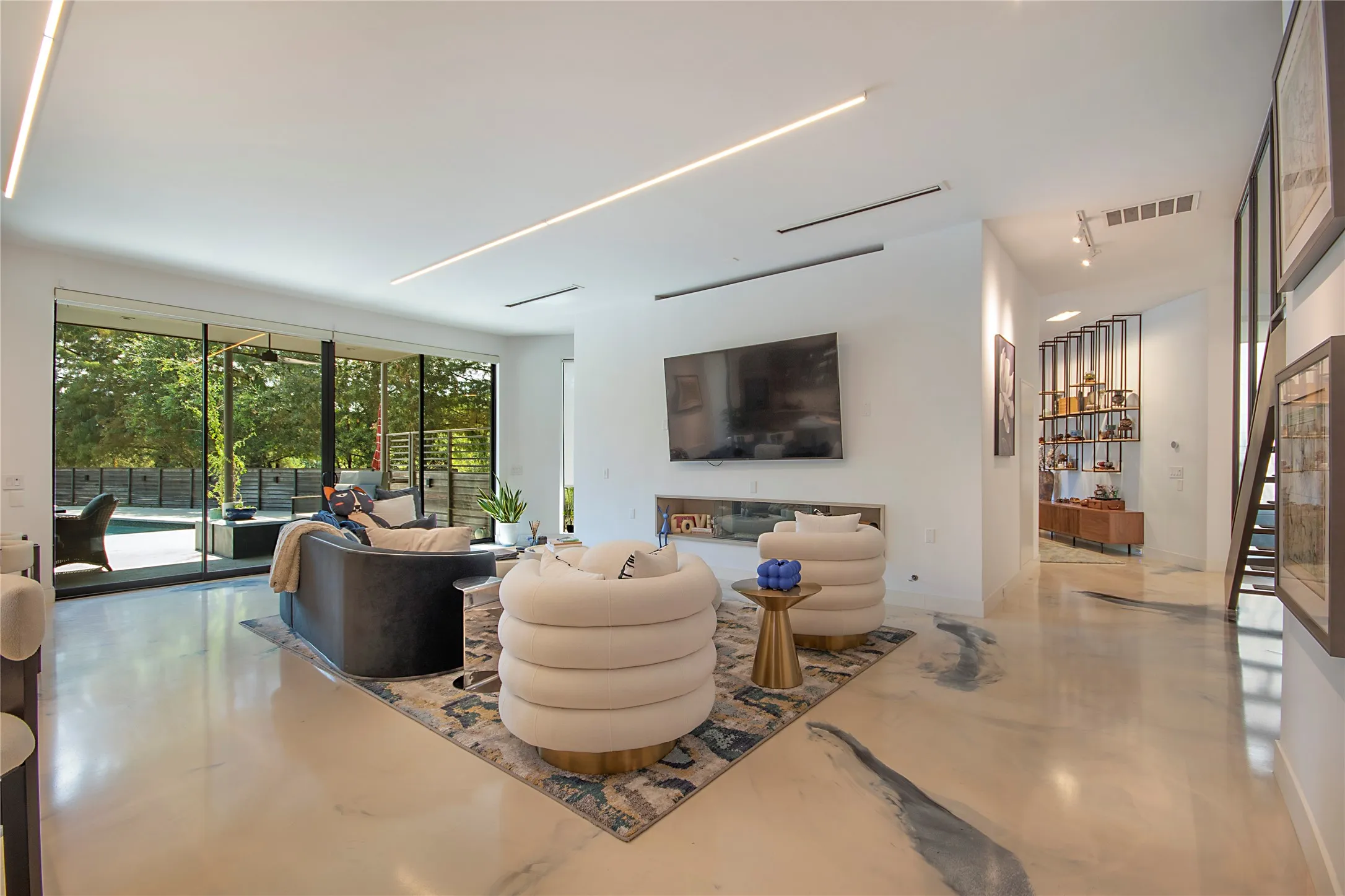 Polished flooring, recessed linear lighting, expansive sliding glass doors, built-in media console, and a contemporary fireplace