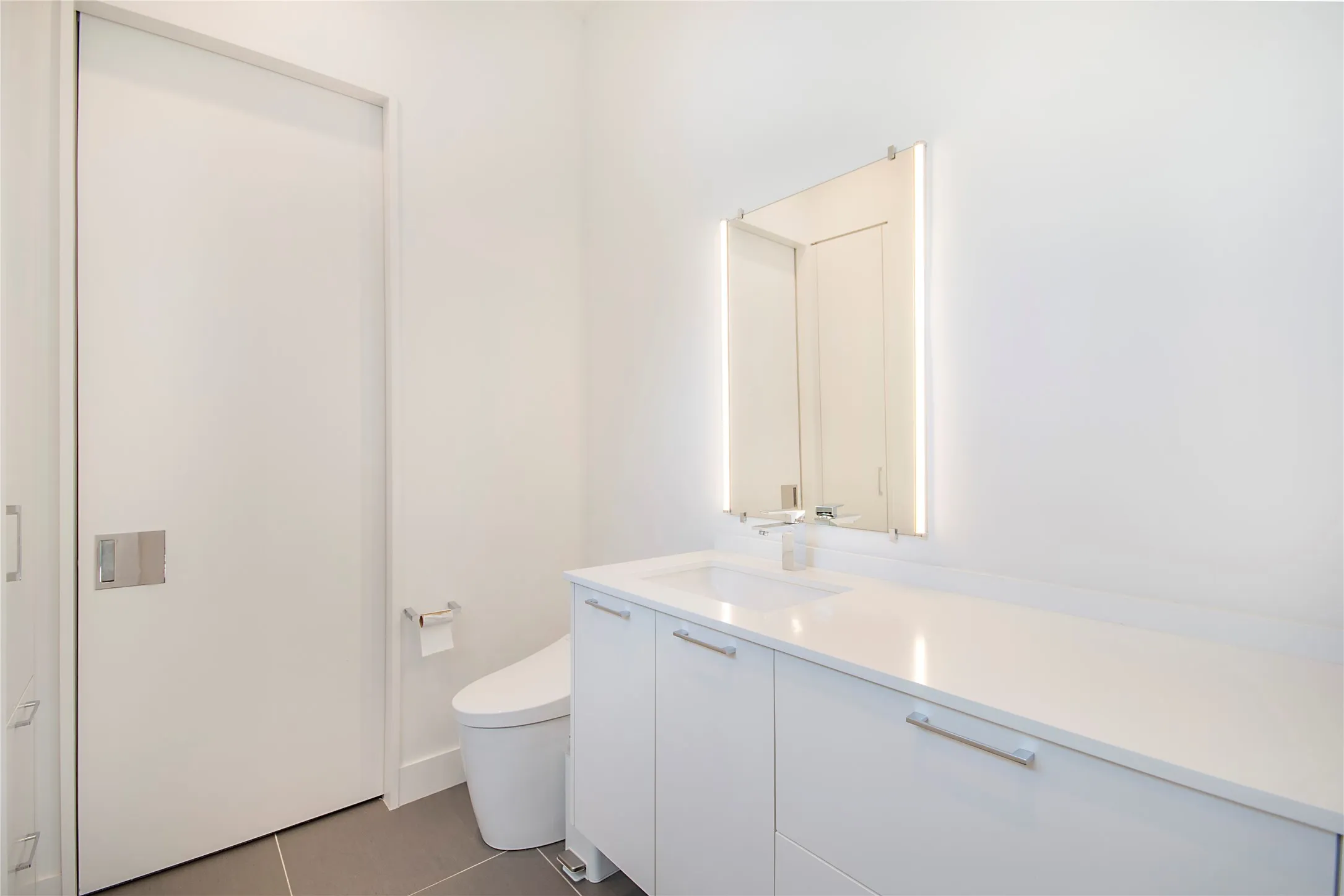 White floating vanity with integrated sink, sleek chrome faucet, and illuminated mirror