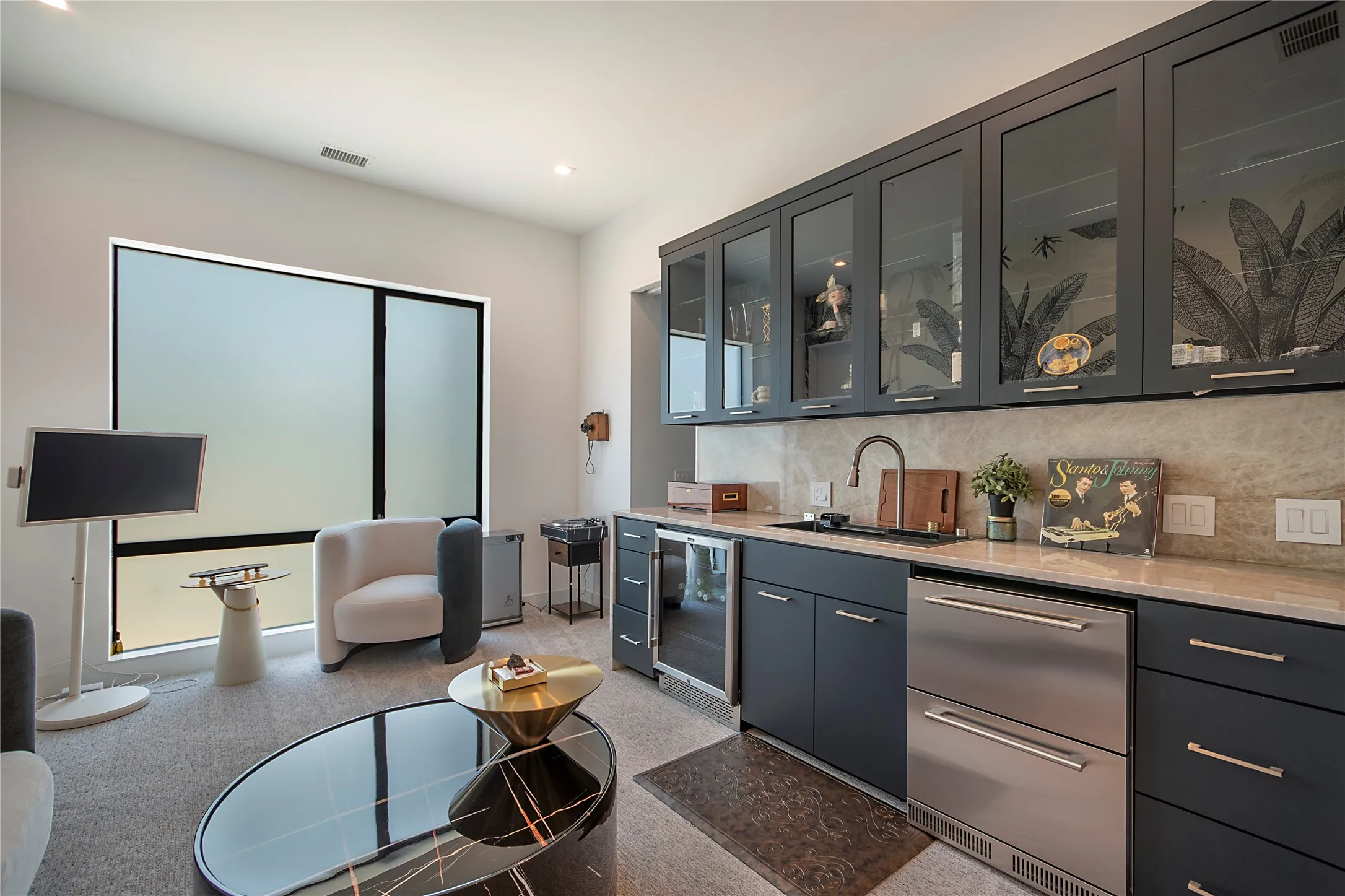 Wet bar featuring gray cabinetry with glass-front uppers, stainless steel appliances, and a light-toned stone countertop and backsplash