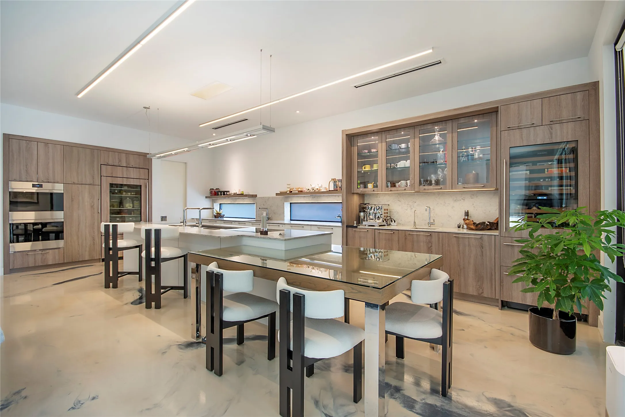 Gourmet kitchen featuring light wood-finish cabinetry, integrated stainless steel appliances, a built-in wine cooler, a large central island, and a separate wet bar area