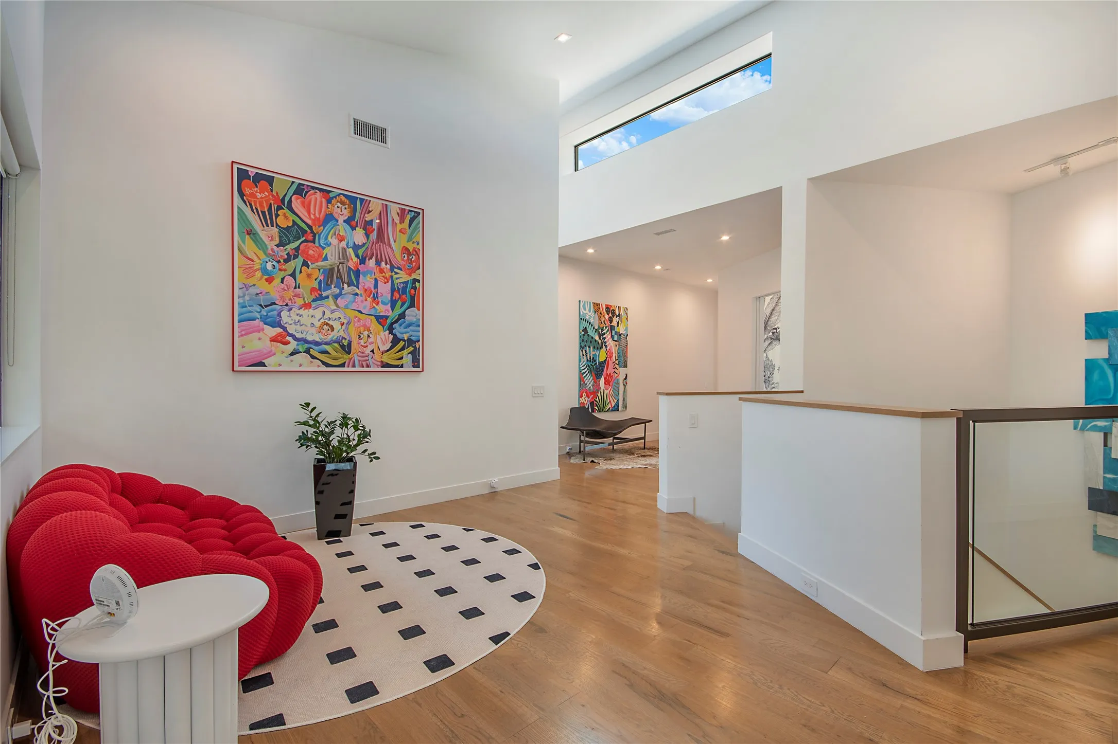High ceilings with transom windows, wood-finish flooring, glass panel railing, recessed lighting, and white walls