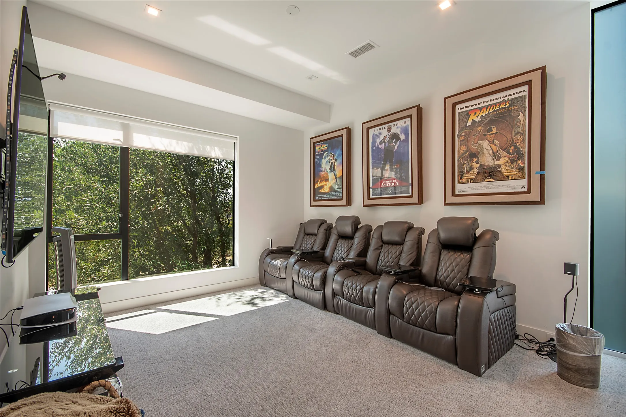 Recessed ceiling lighting, large window with roller shade, wall-mounted television, and light-colored carpeting