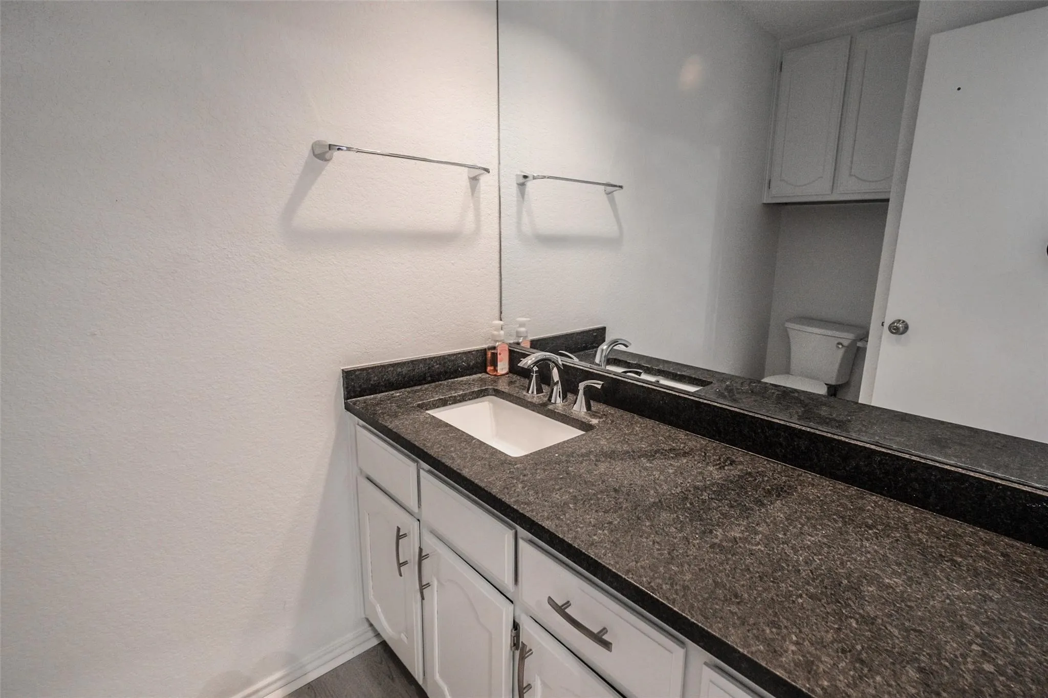 Vanity with stone-finish countertop, integrated sink, and chrome fixtures