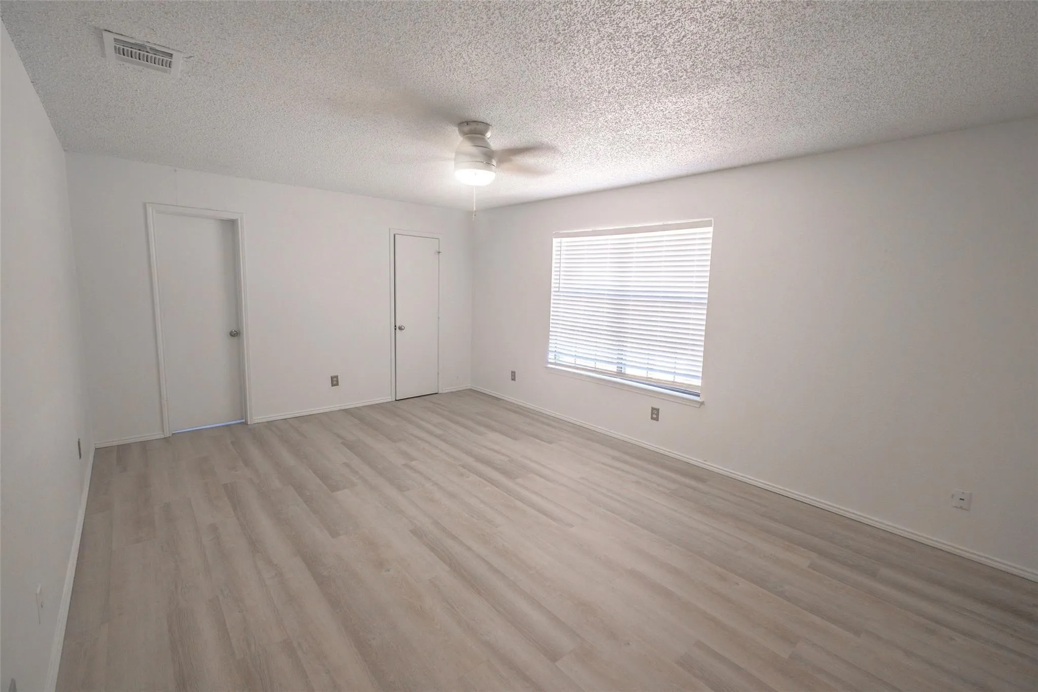 Spacious interior featuring wood-finish flooring, white walls, and a ceiling fan