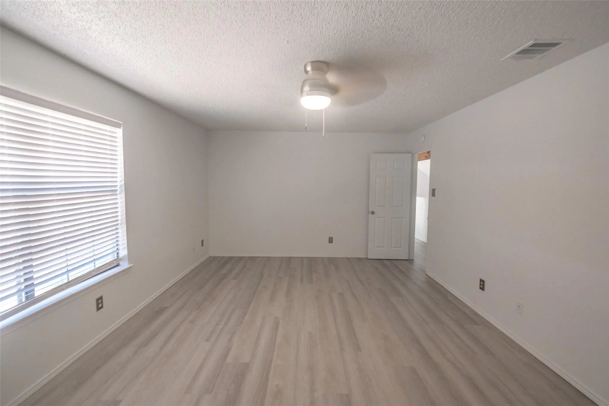 Wood-finish flooring, white walls, and a ceiling fan with integrated lighting