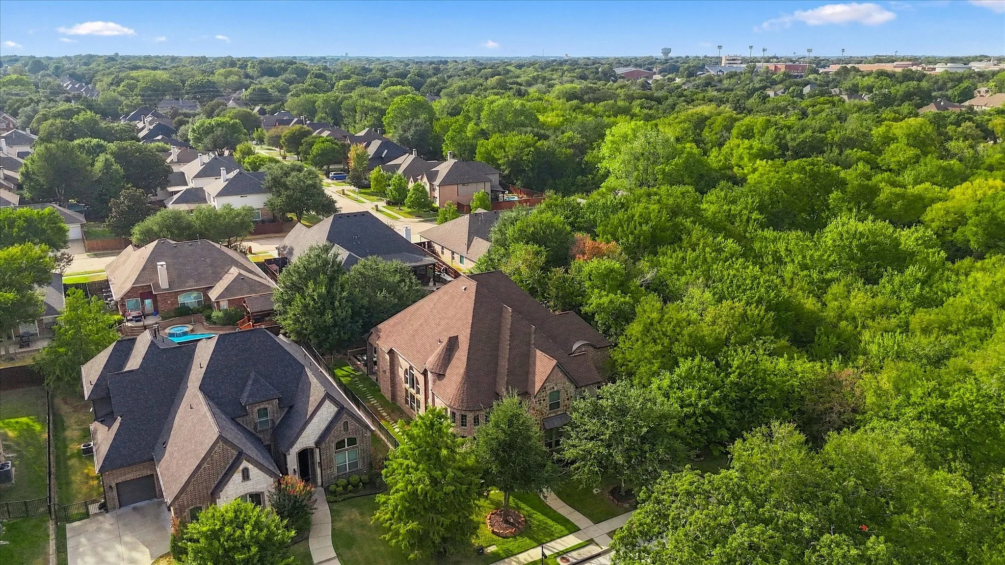 Aerial perspective showcasing a residential neighborhood with dense mature trees and varied rooflines