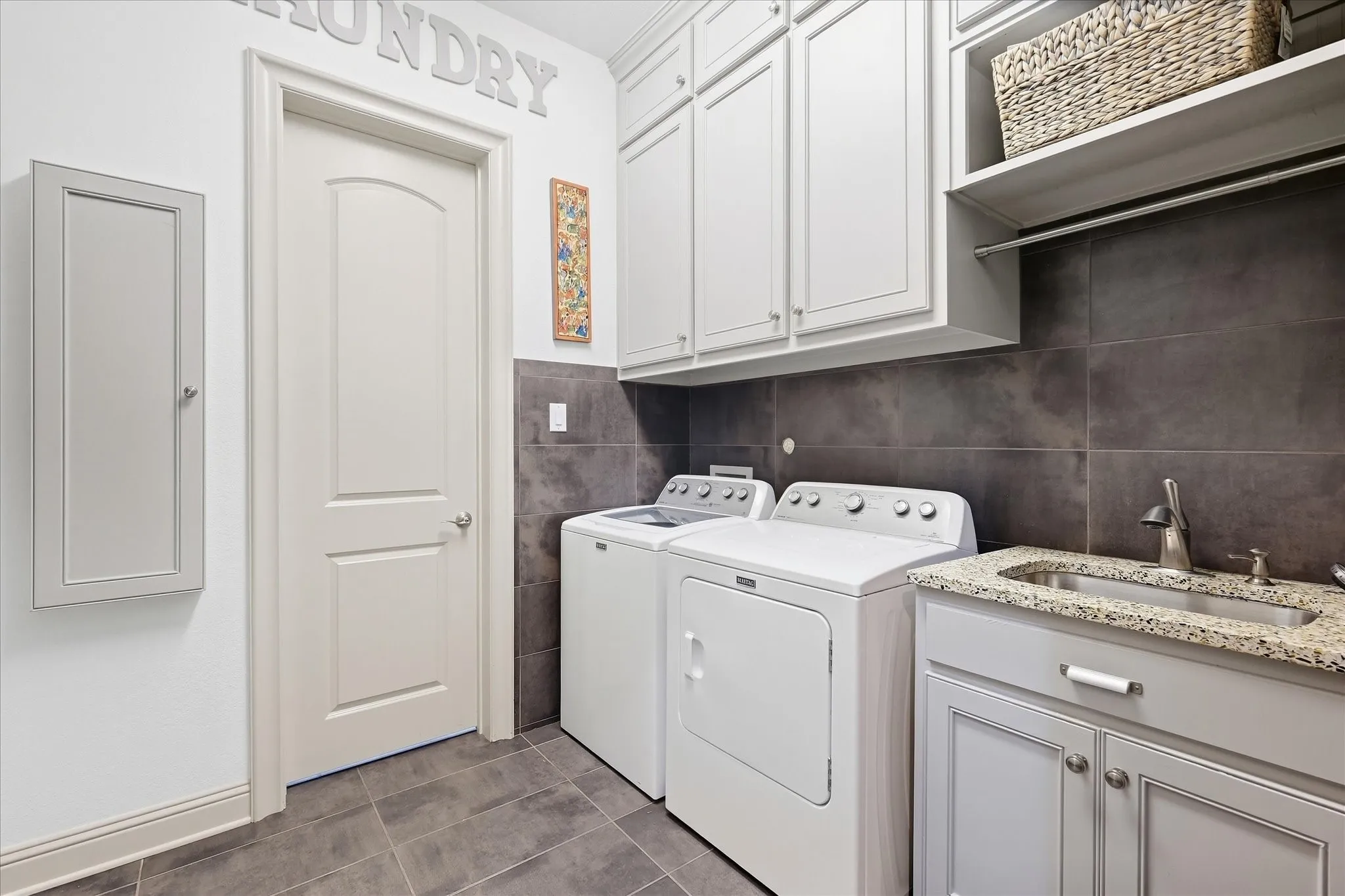 Integrated sink with a stone countertop, built-in cabinetry, upper storage cabinets, tiled walls, and tiled flooring