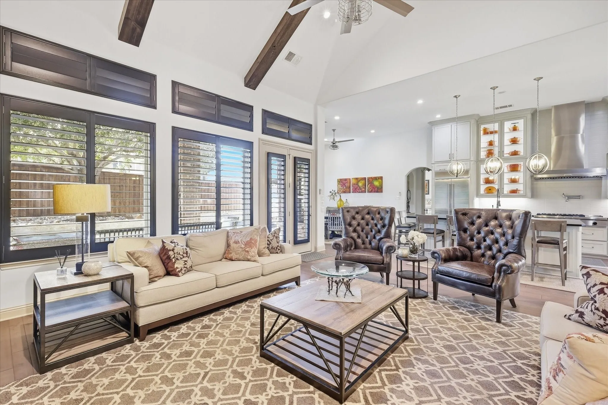 Vaulted ceiling with exposed wood beams, plantation shutters, woodflooring, recessed lighting, and a kitchen featuring a stainless steel range hood