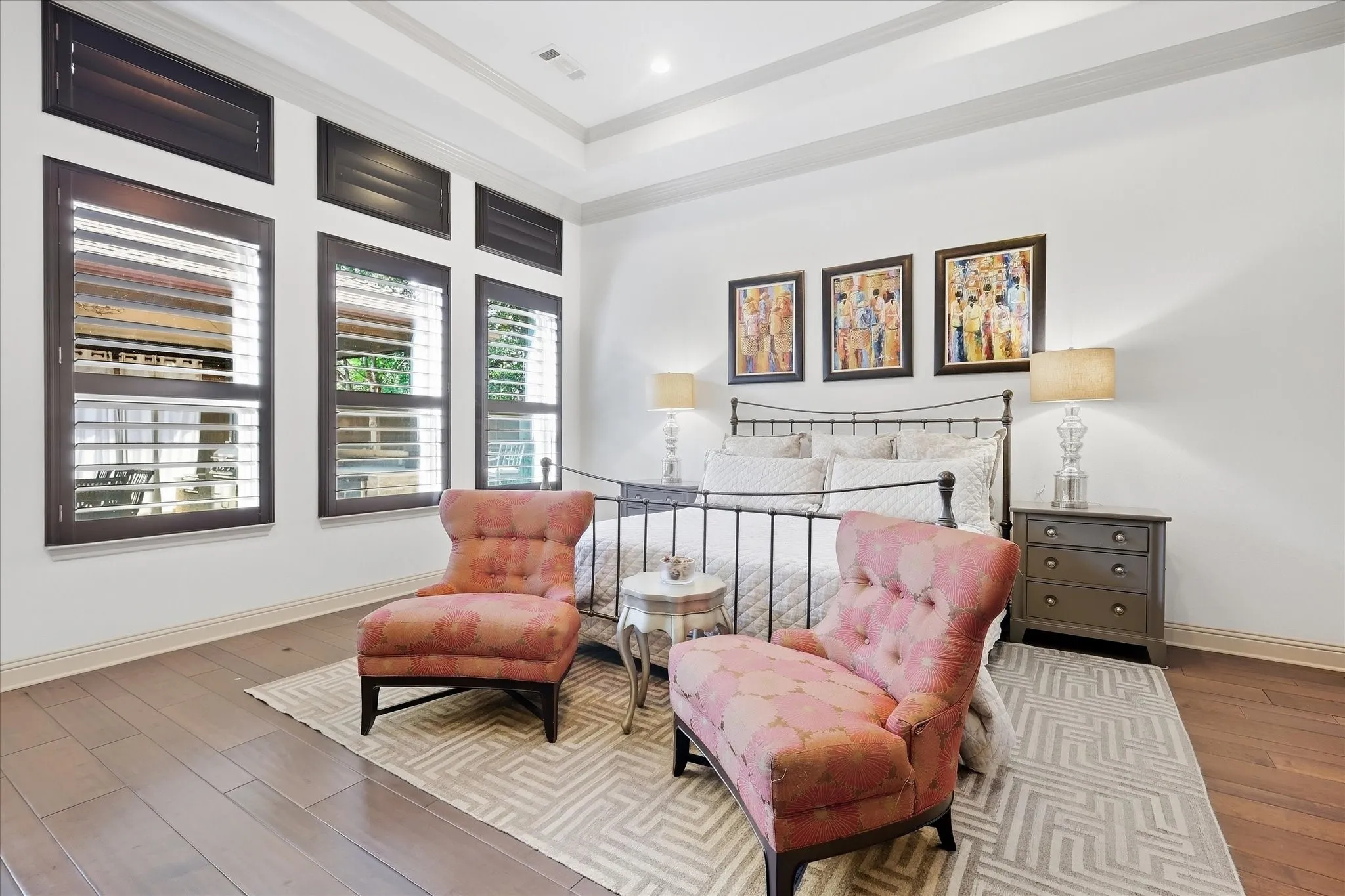Wood-finish flooring, plantation shutters, and a tray ceiling create a refined aesthetic