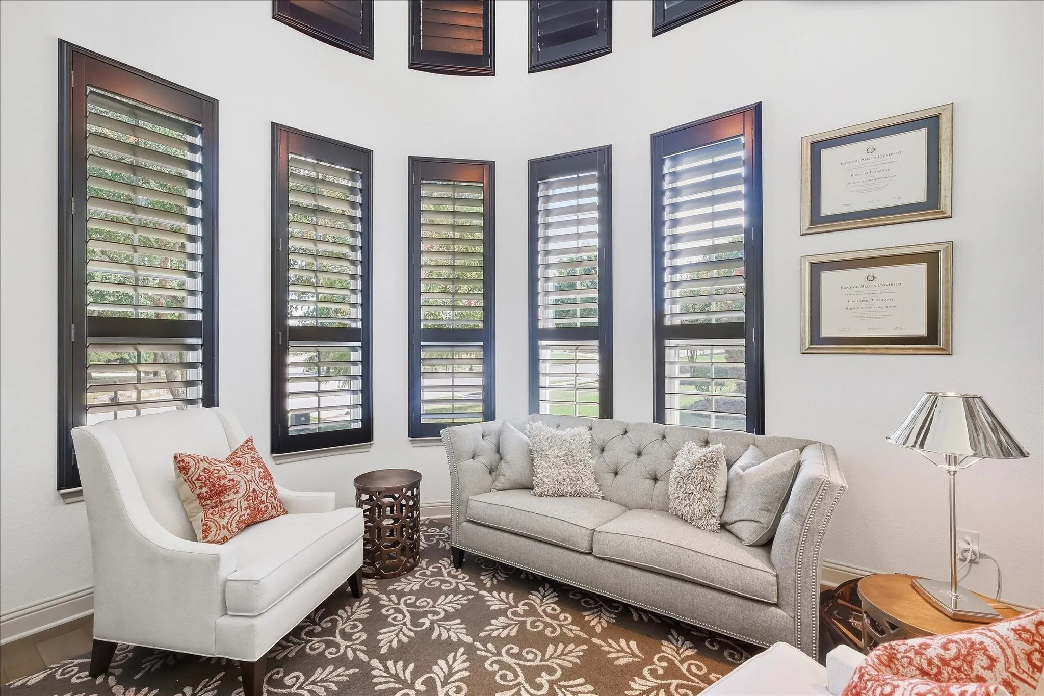 Curved wall featuring multiple tall windows with dark plantation shutters