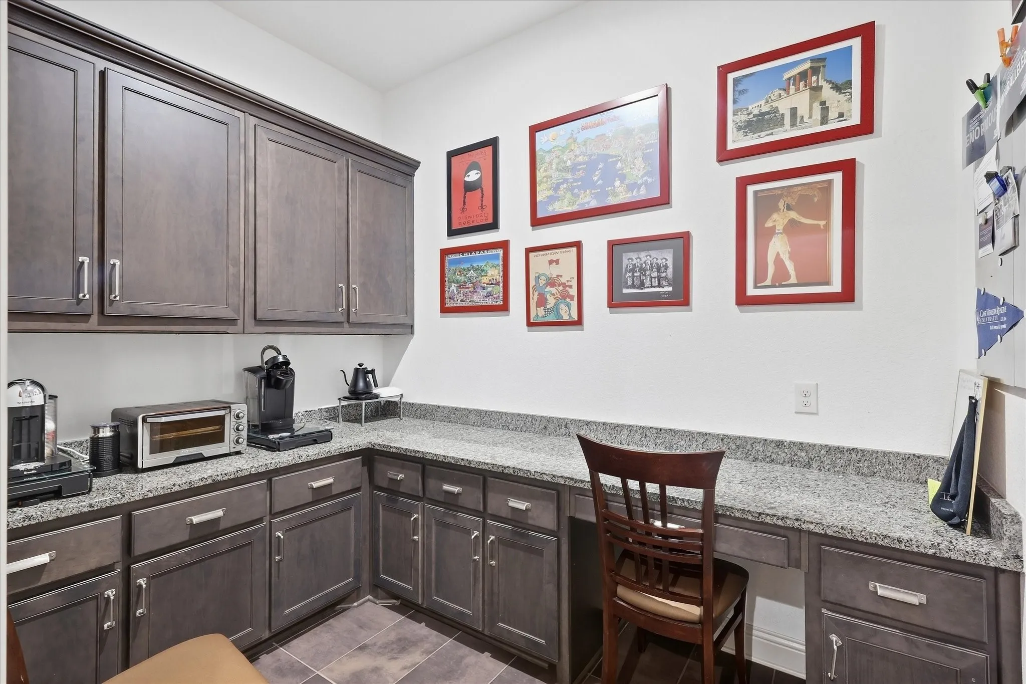 Prep kitchen area or office flex space with Built-in desk with a stone-finish countertop, dedicated cabinet storage, and dark wood-finish cabinetry