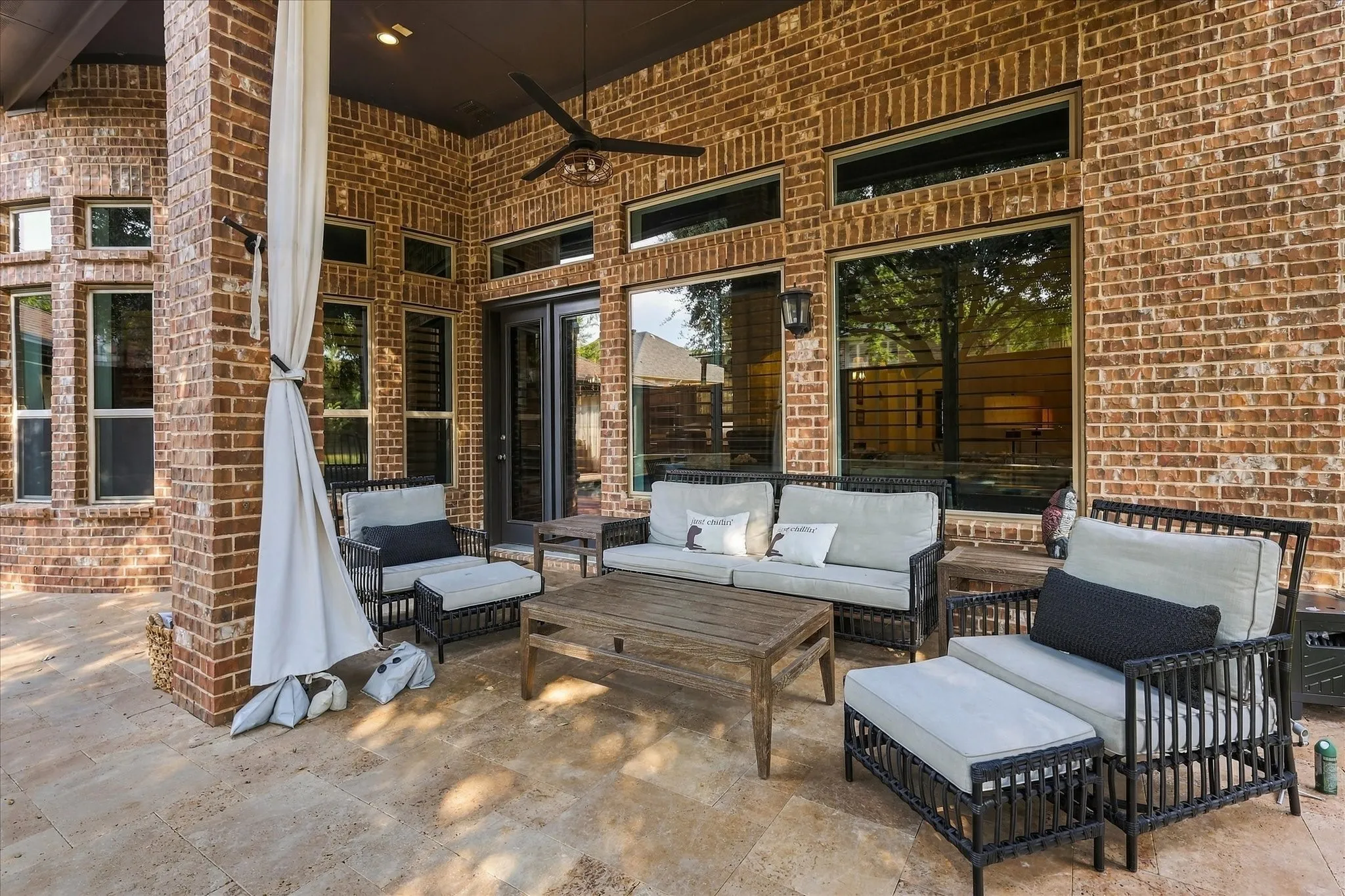Brick exterior with multiple windows, French doors, patio with tile flooring, and a ceiling fan