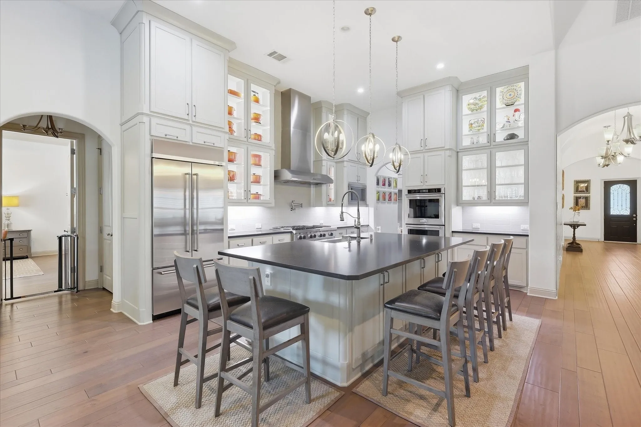 Gourmet kitchen with stainless steel appliances, a large center island, pendant lighting, and light wood-finish flooring