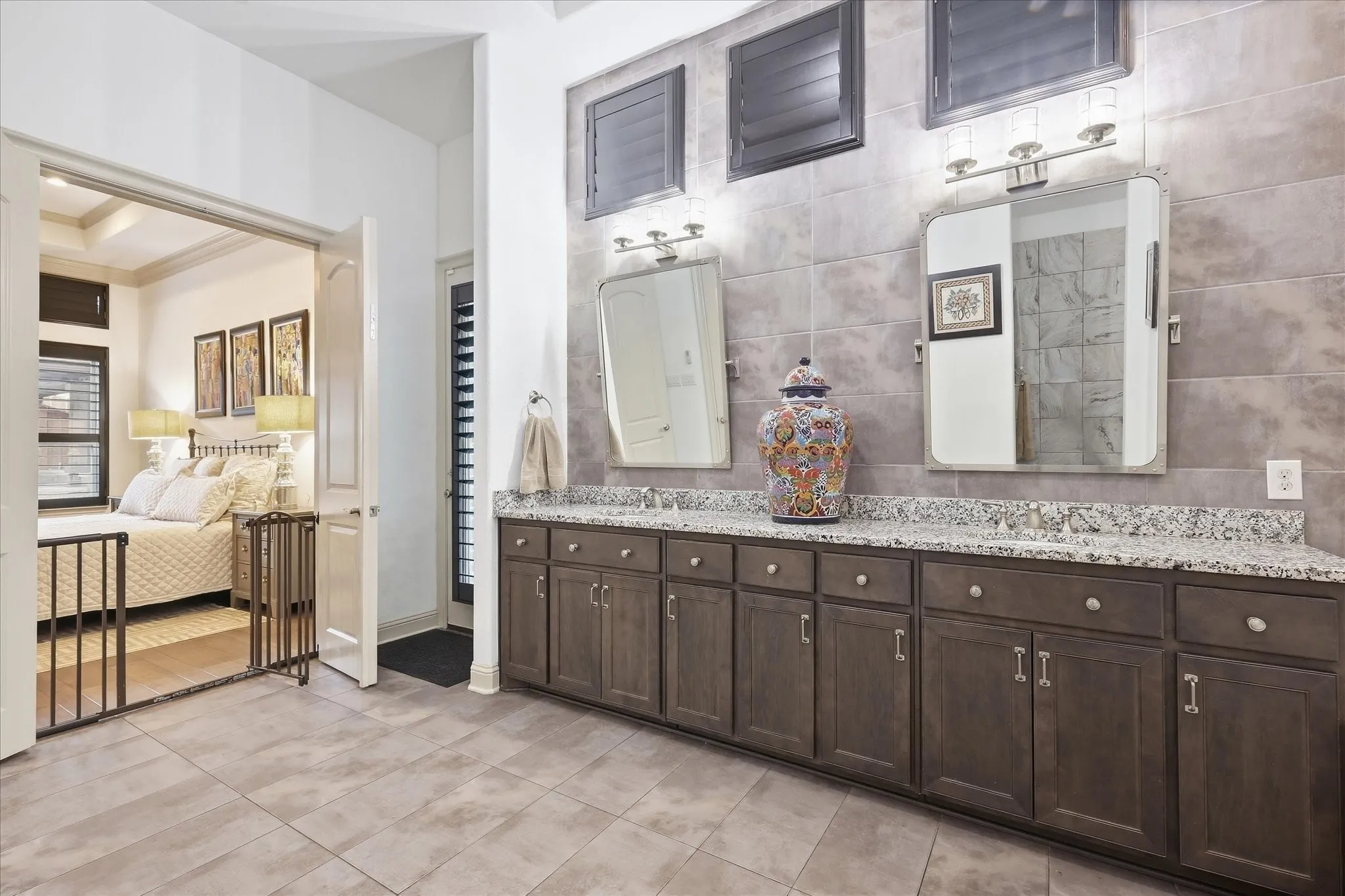 Dual vanity with granite countertop, wood-finish cabinetry, and tiled backsplash