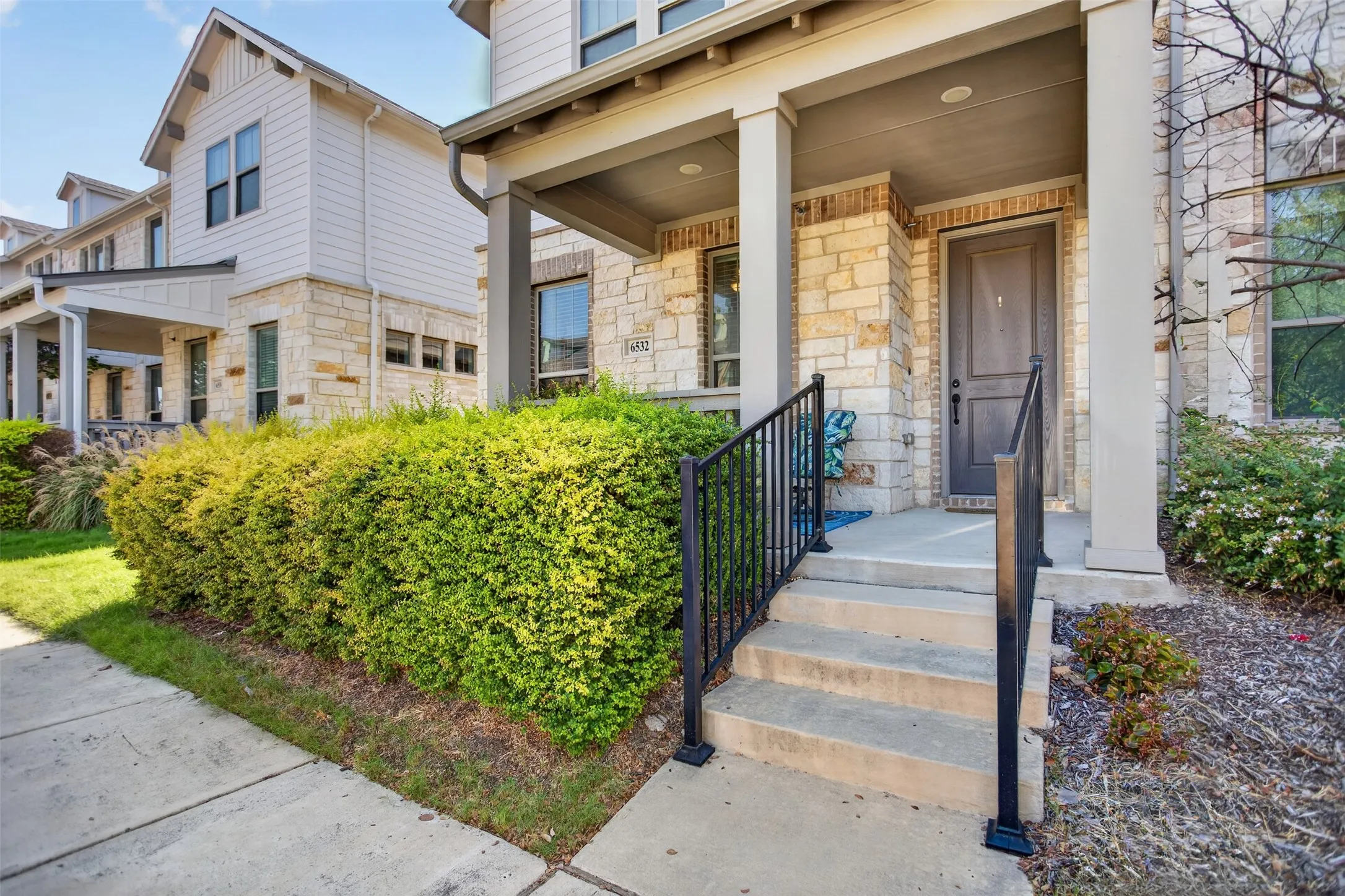 Stone and siding exterior with a covered porch entry, concrete steps, and a dark paneled door