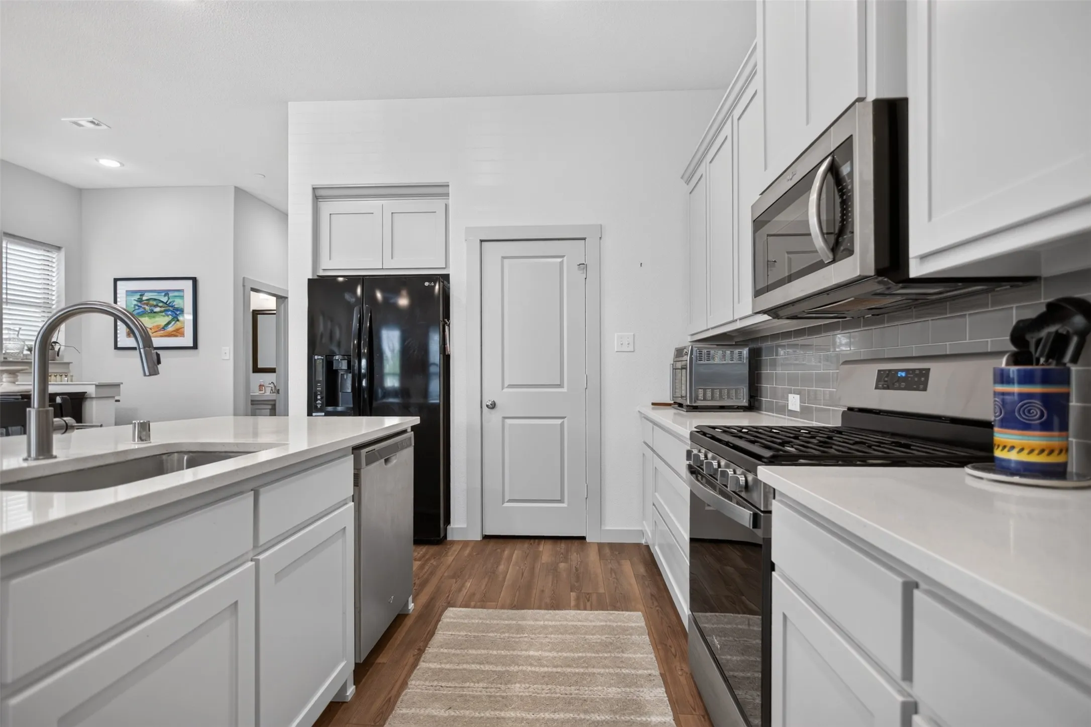 Kitchen featuring light-toned cabinetry, stainless steel appliances, white countertops, and a subway tile backsplash