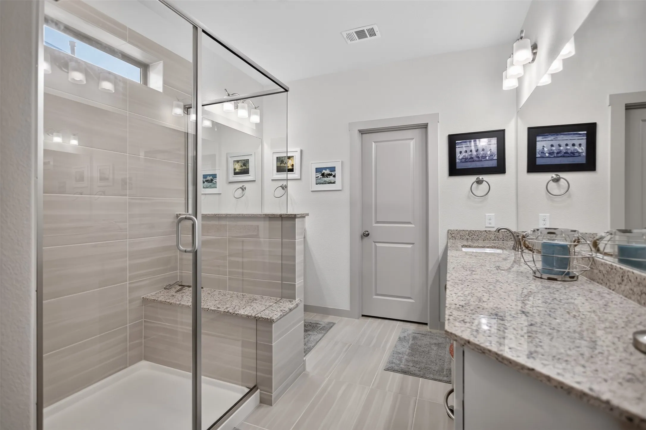 Glass-enclosed shower with a built-in bench and light-toned tile surround