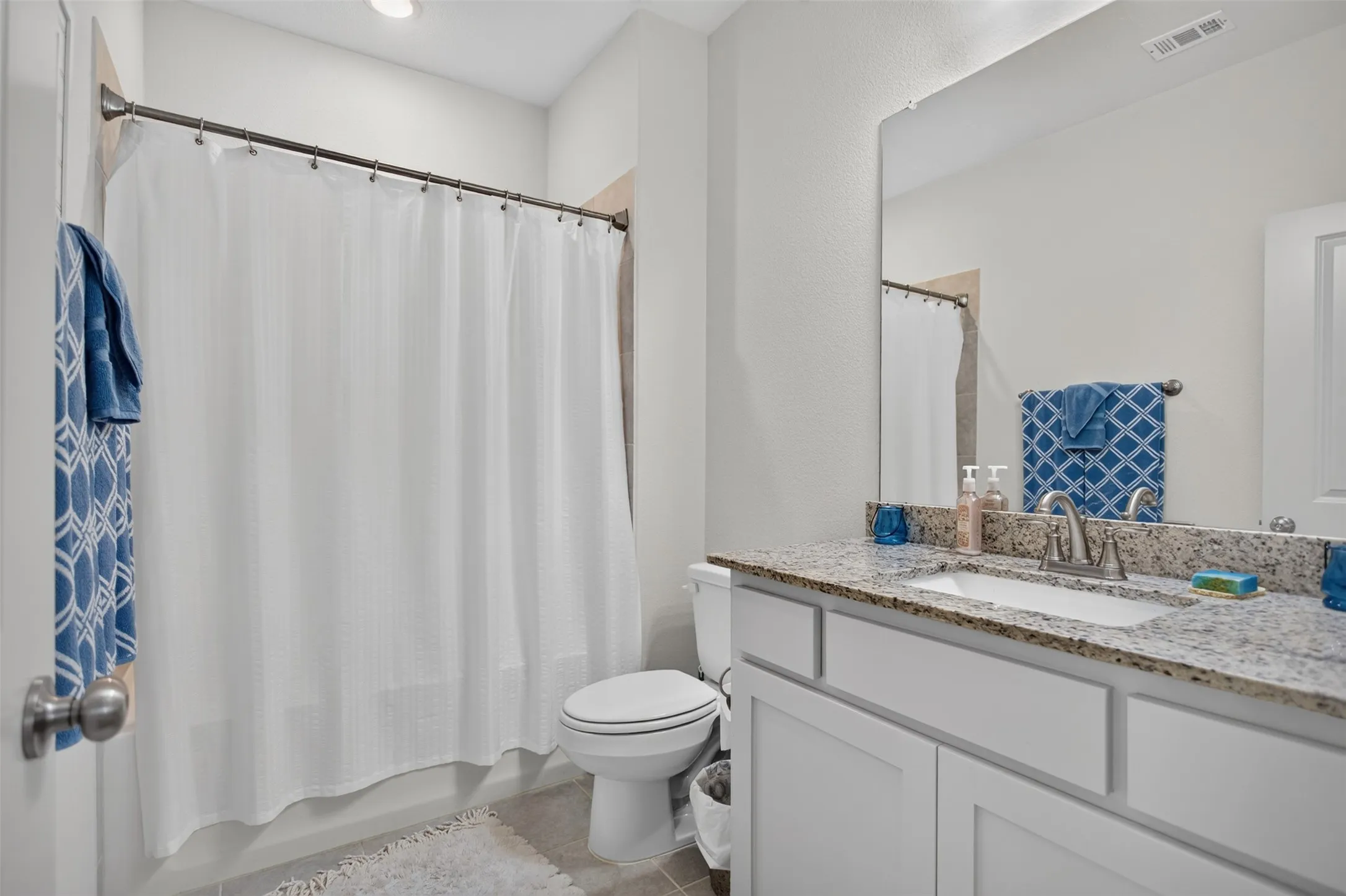 Granite-style countertop, white cabinetry with brushed nickel hardware, and an undermount sink