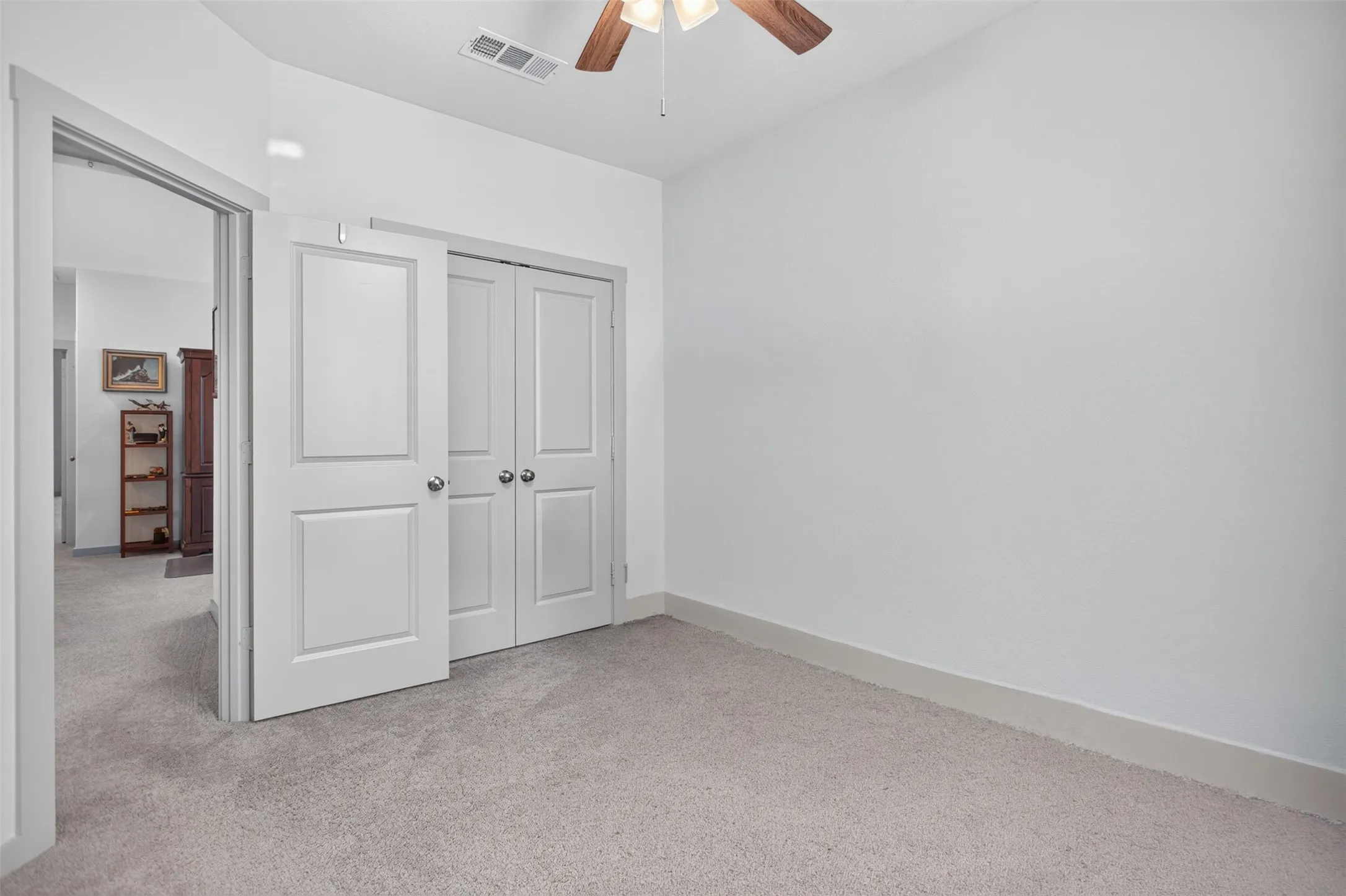 Neutral wall colors, light-toned carpet, and a ceiling fan