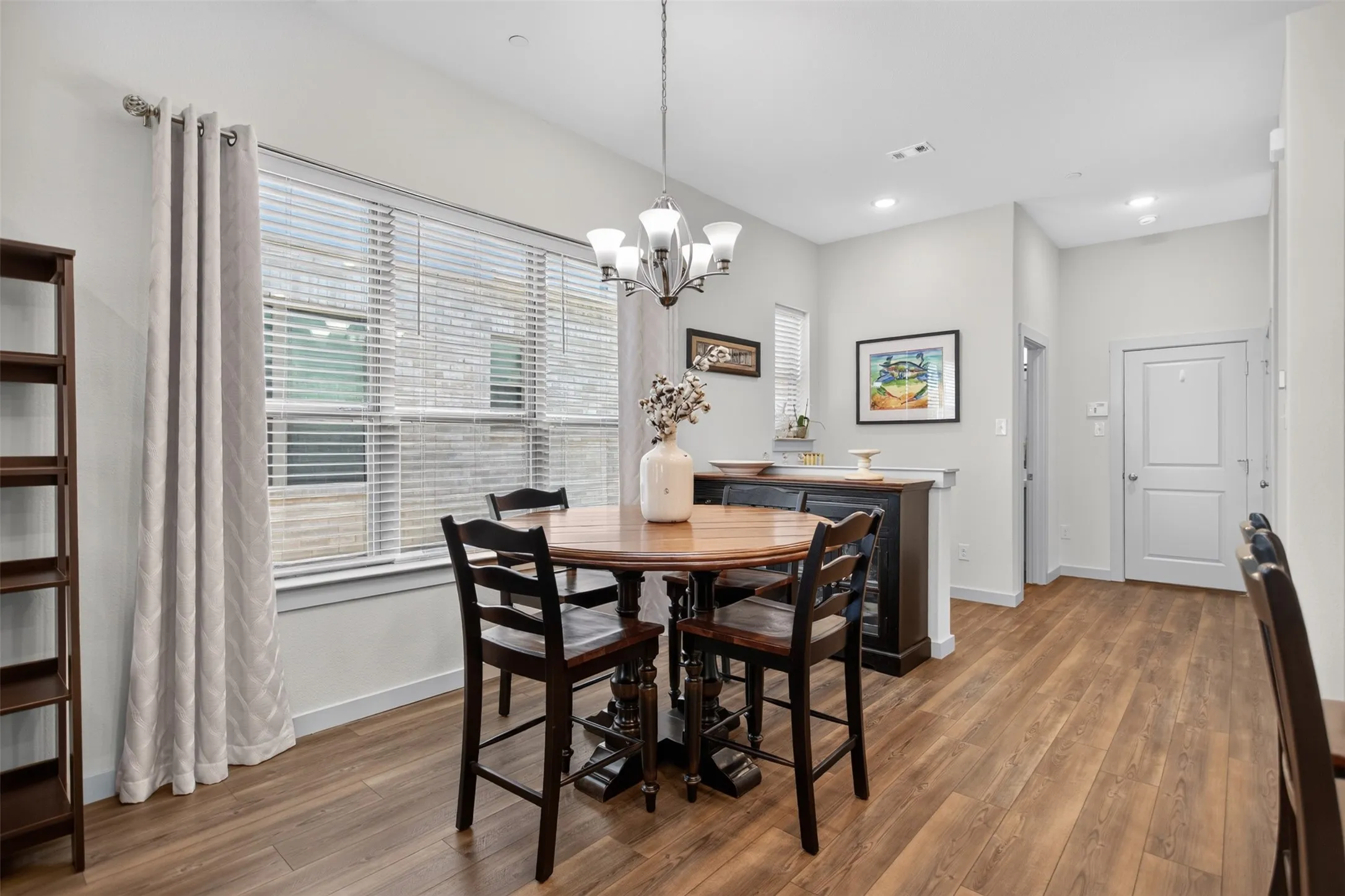 Wood-finish flooring, recessed lighting, and a chandelier illuminate the space