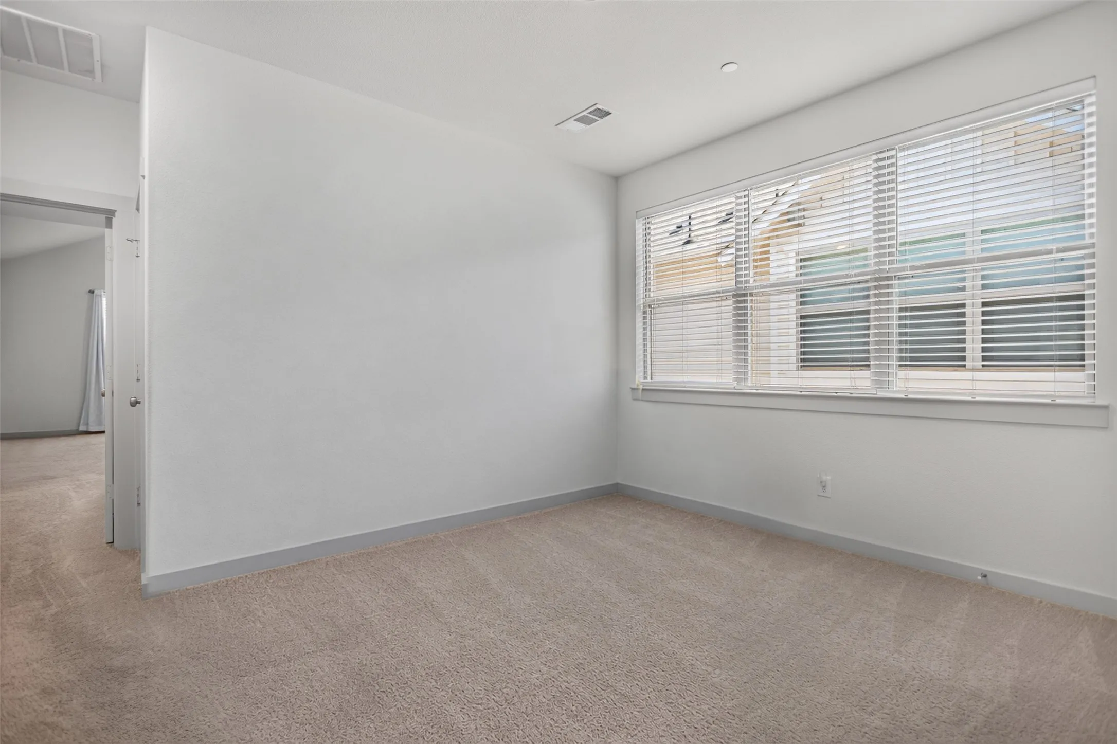 Recessed lighting, carpeted flooring, large window with blinds, and white painted walls