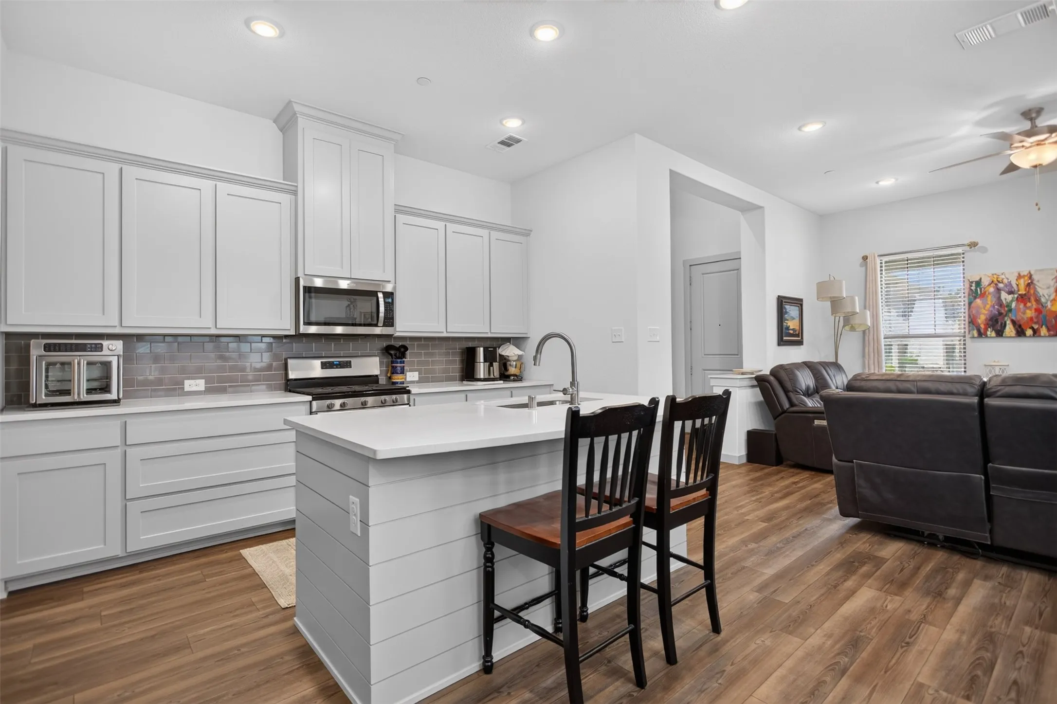 Kitchen island with shiplap-style paneling, white countertop, and integrated sink