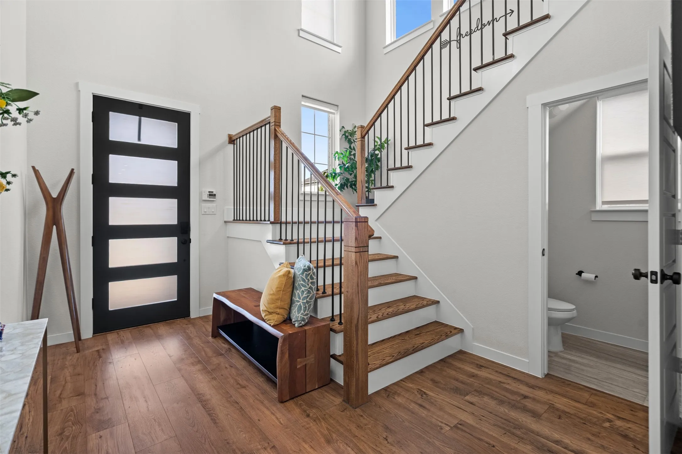 Wood-finish flooring throughout, featuring a modern black entry door with frosted glass panels