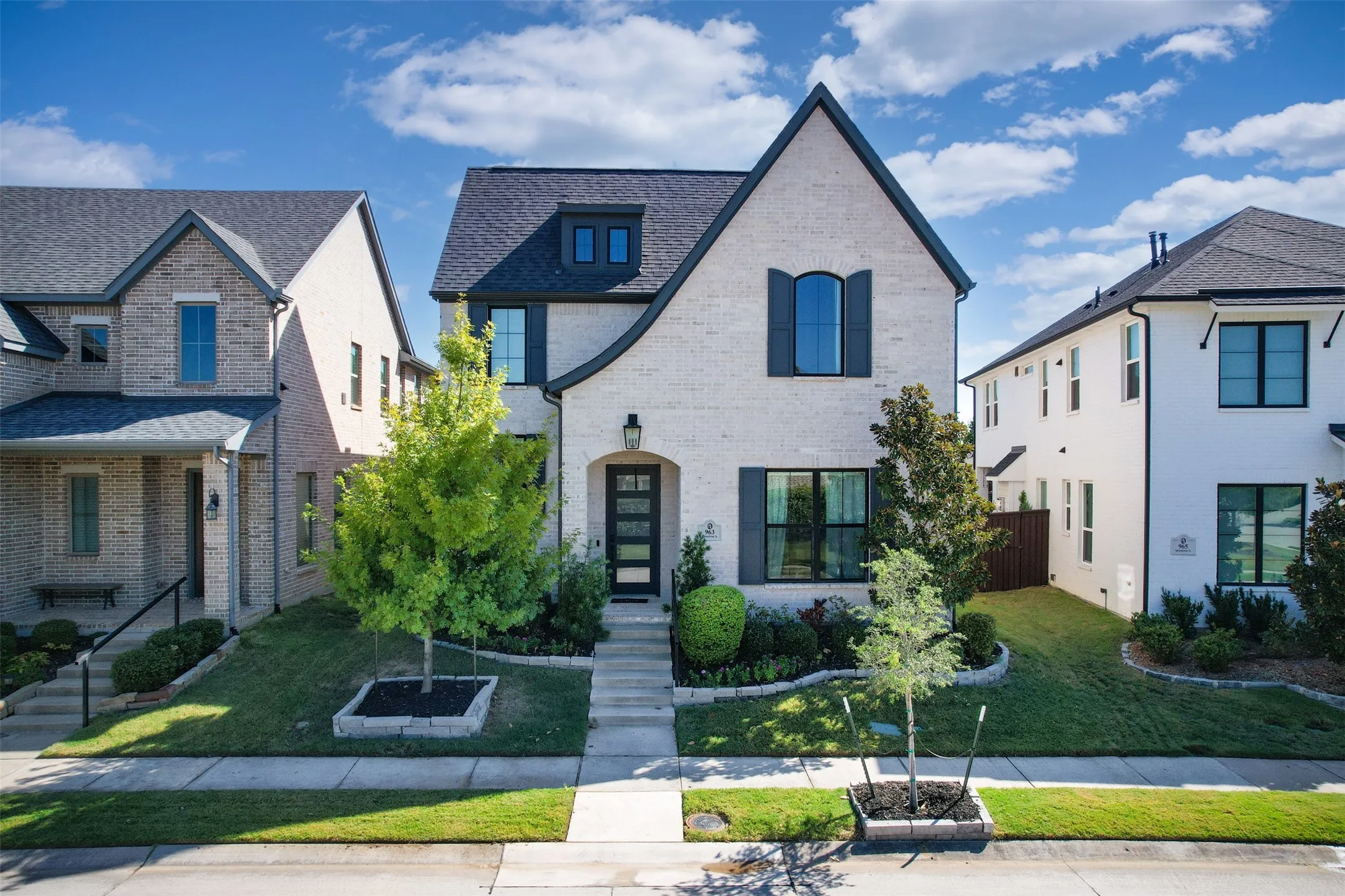 Brick exterior, black-framed windows, dark gray shutters, dark gray roof, and a prominent front entrance