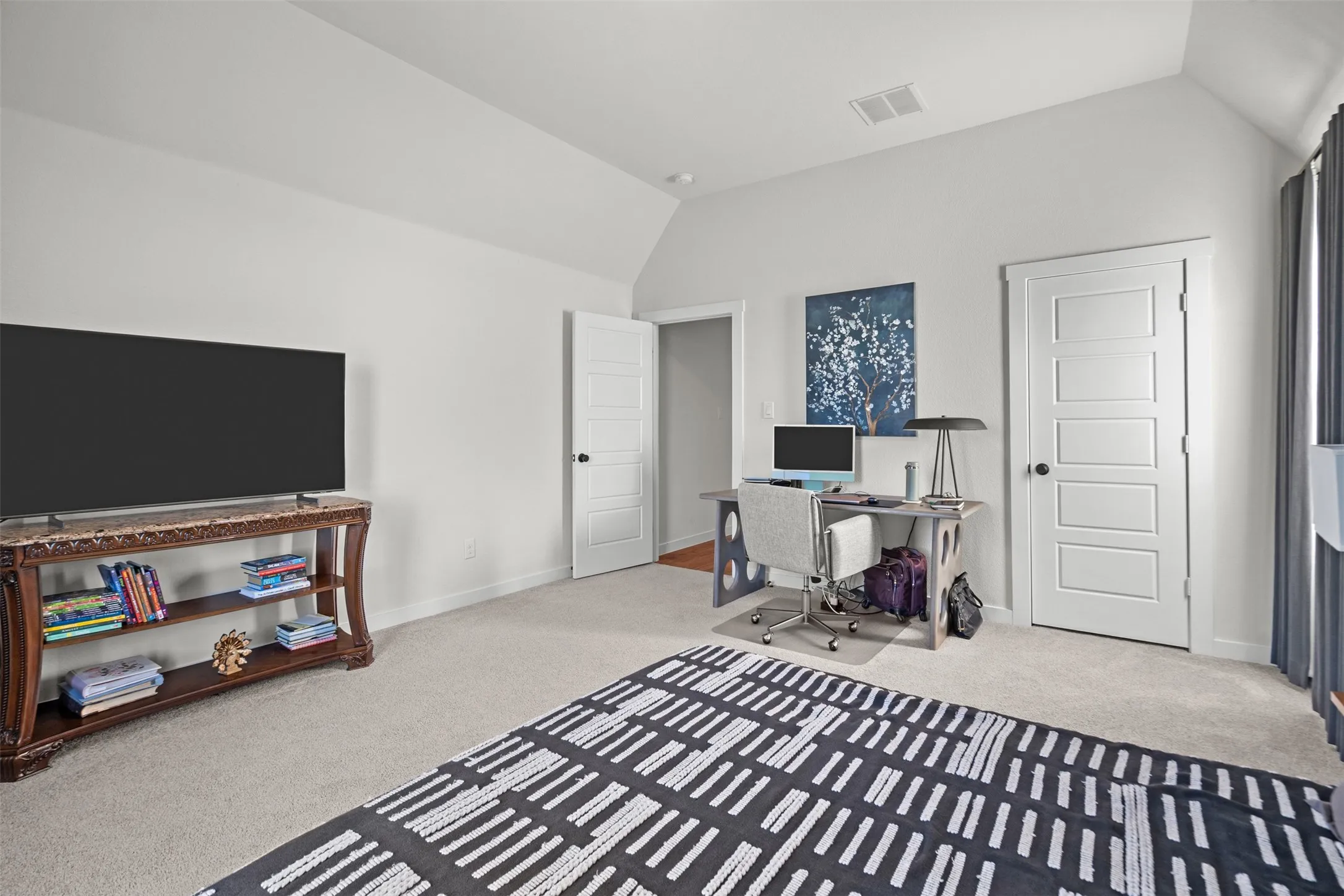 Vaulted ceiling, carpeted flooring, paneled interior doors, and a built-in ventilation system