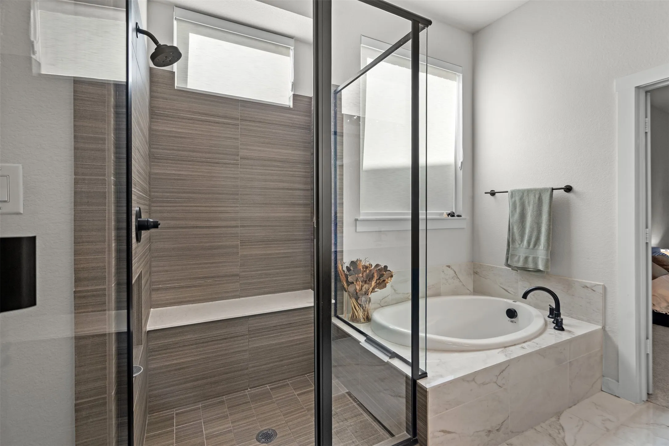 Enclosed shower with horizontal-set tile, built-in bench, and dark-finish fixtures