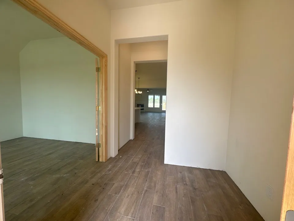 Wood-finish flooring throughout, light-toned wall paint, and arched doorway