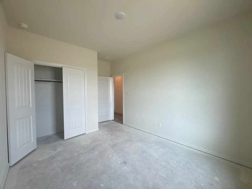 Neutral wall finish, ceiling-mounted lighting, and a bi-fold closet